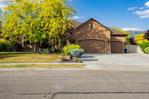 Stucco exterior property featuring a multi-car garage, concrete driveway, and mature landscaping