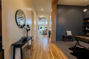 Hardwood flooring extending through the entry corridor, with recessed lighting and a contrasting dark accent wall
