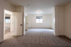 Spacious interior room with neutral carpeting and white painted walls