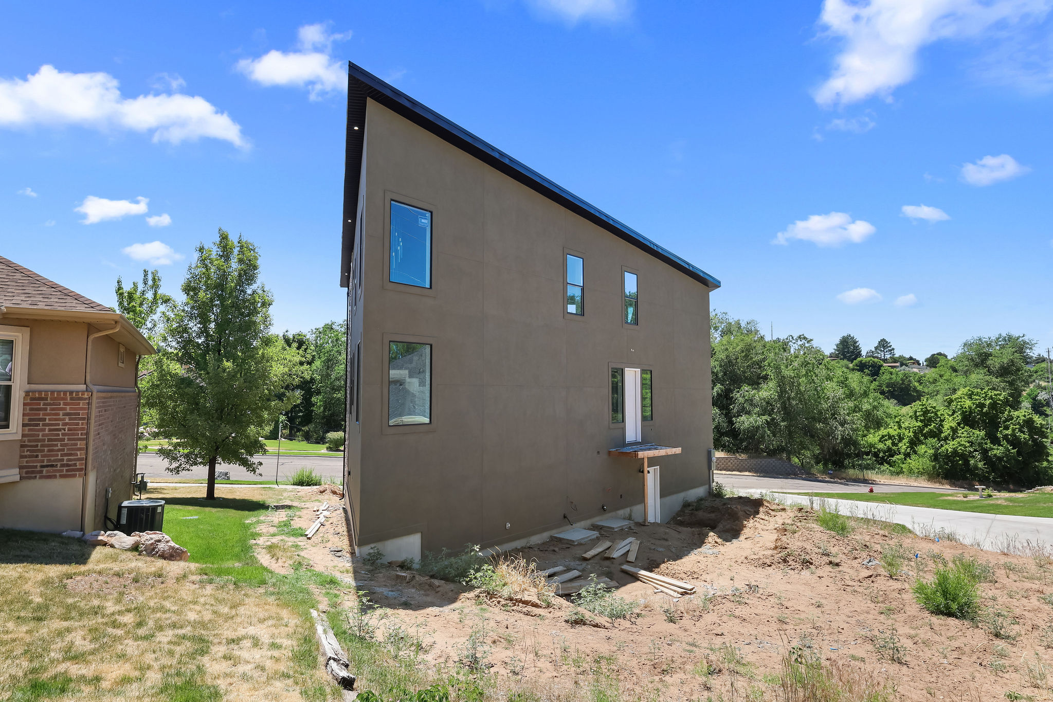 Contemporary residence featuring a dark stucco exterior, a striking sloped roofline, and multiple vertical windows