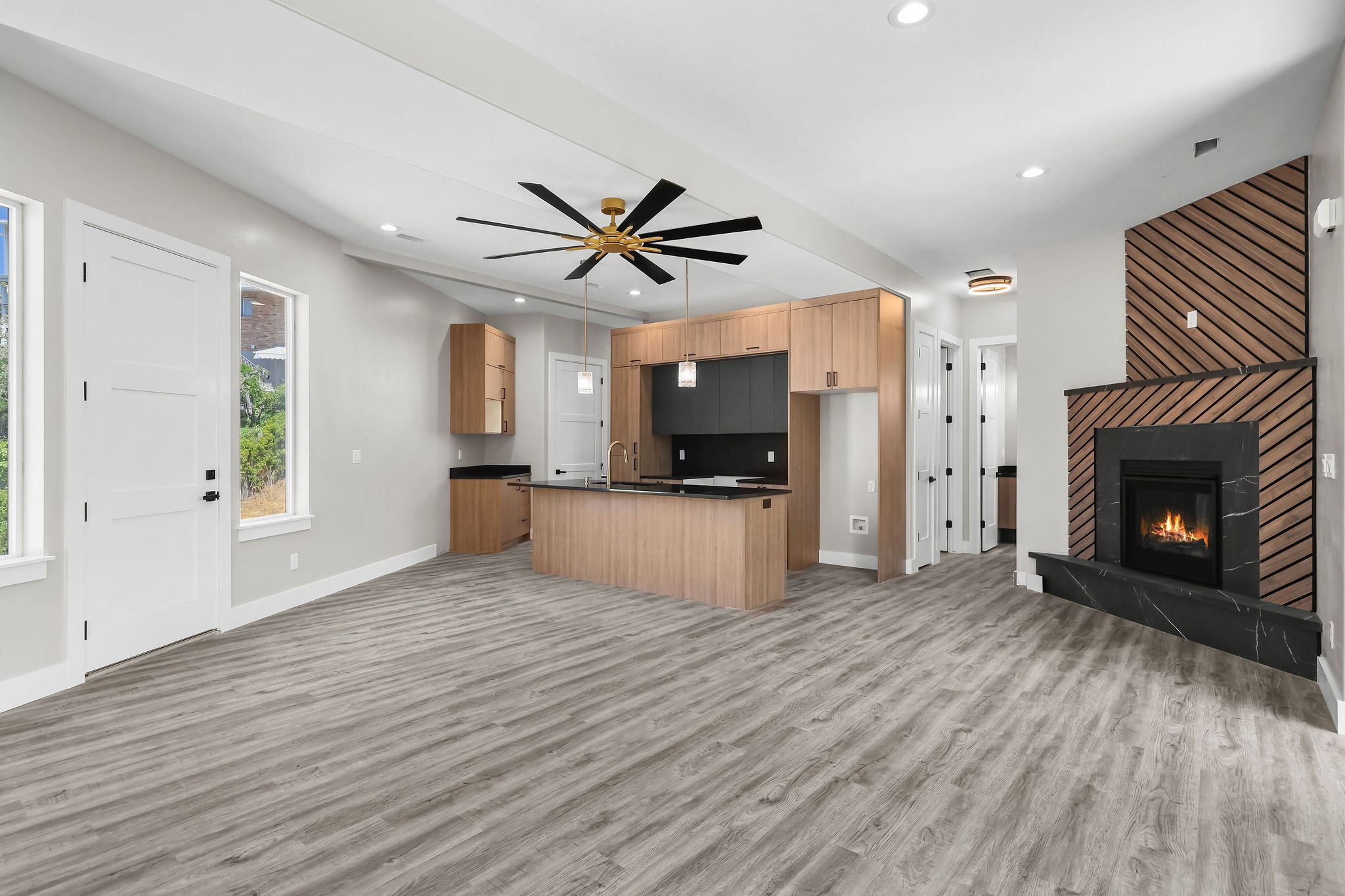 Open-concept living area featuring wood-finish flooring and a contemporary fireplace with a black stone surround and wood slat accent wall