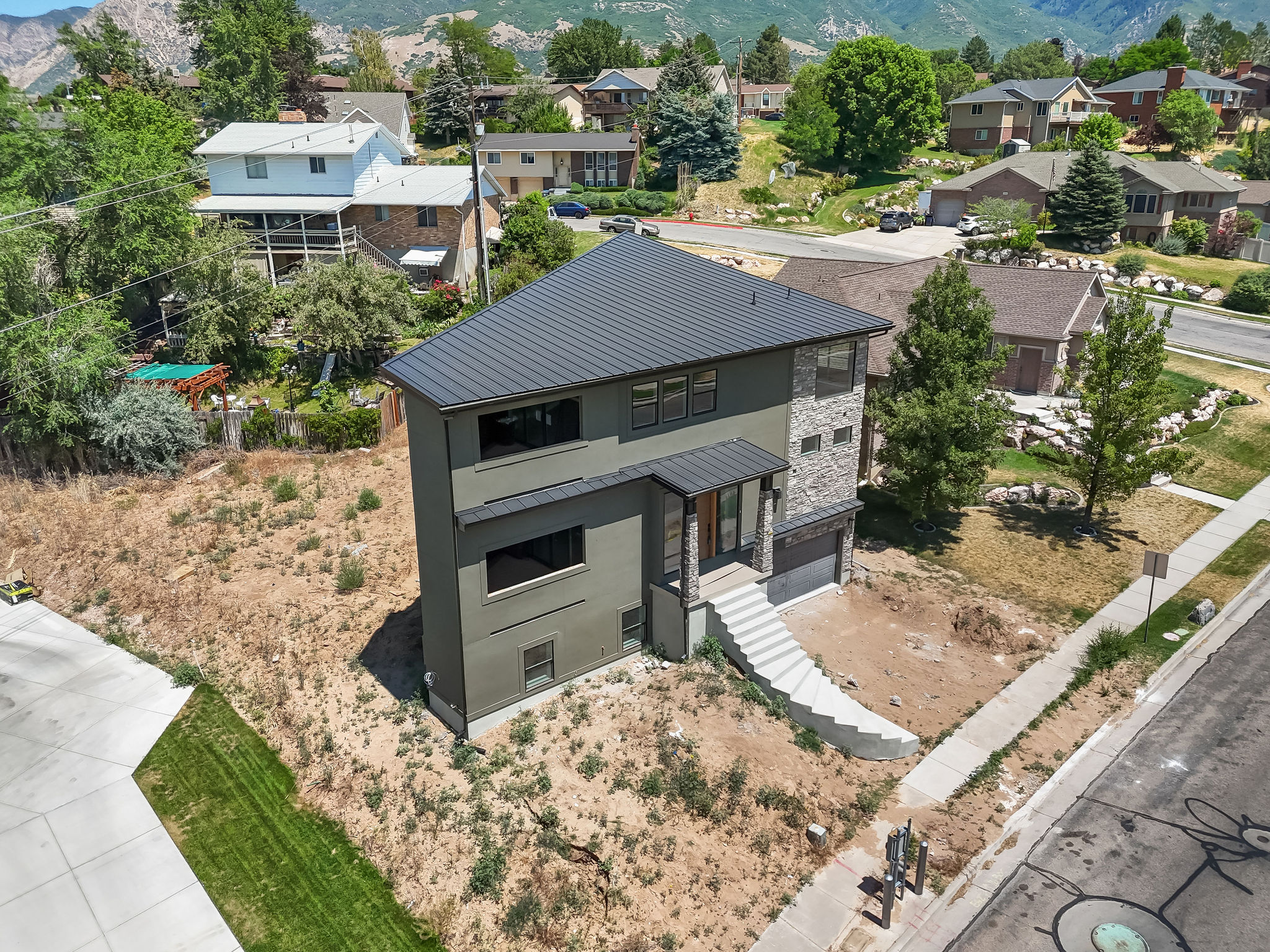 Contemporary two-story residence with a dark metal roof and stone veneer accents