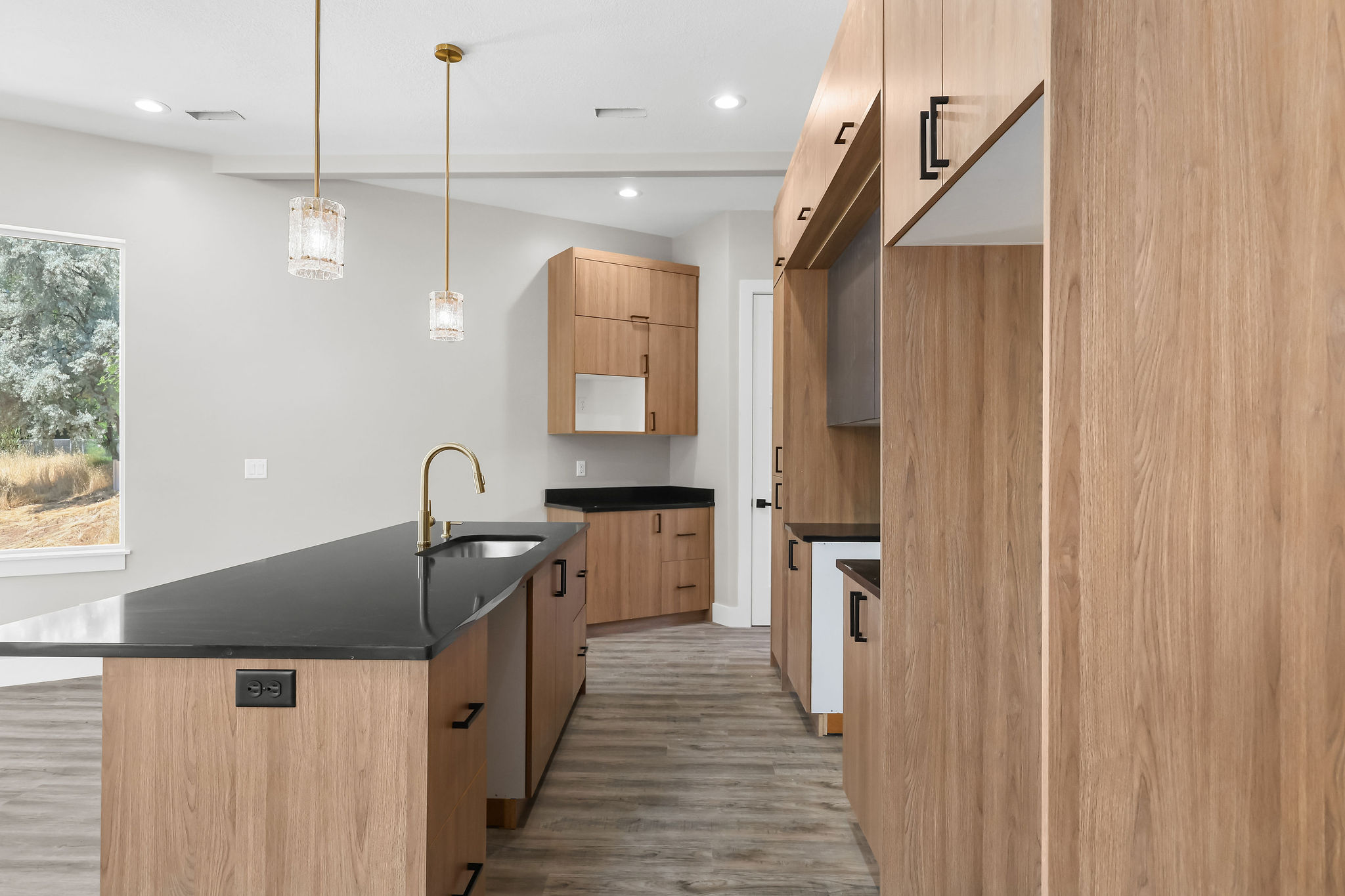 Kitchen featuring a dark countertop island with an undermount sink and gold-finish faucet