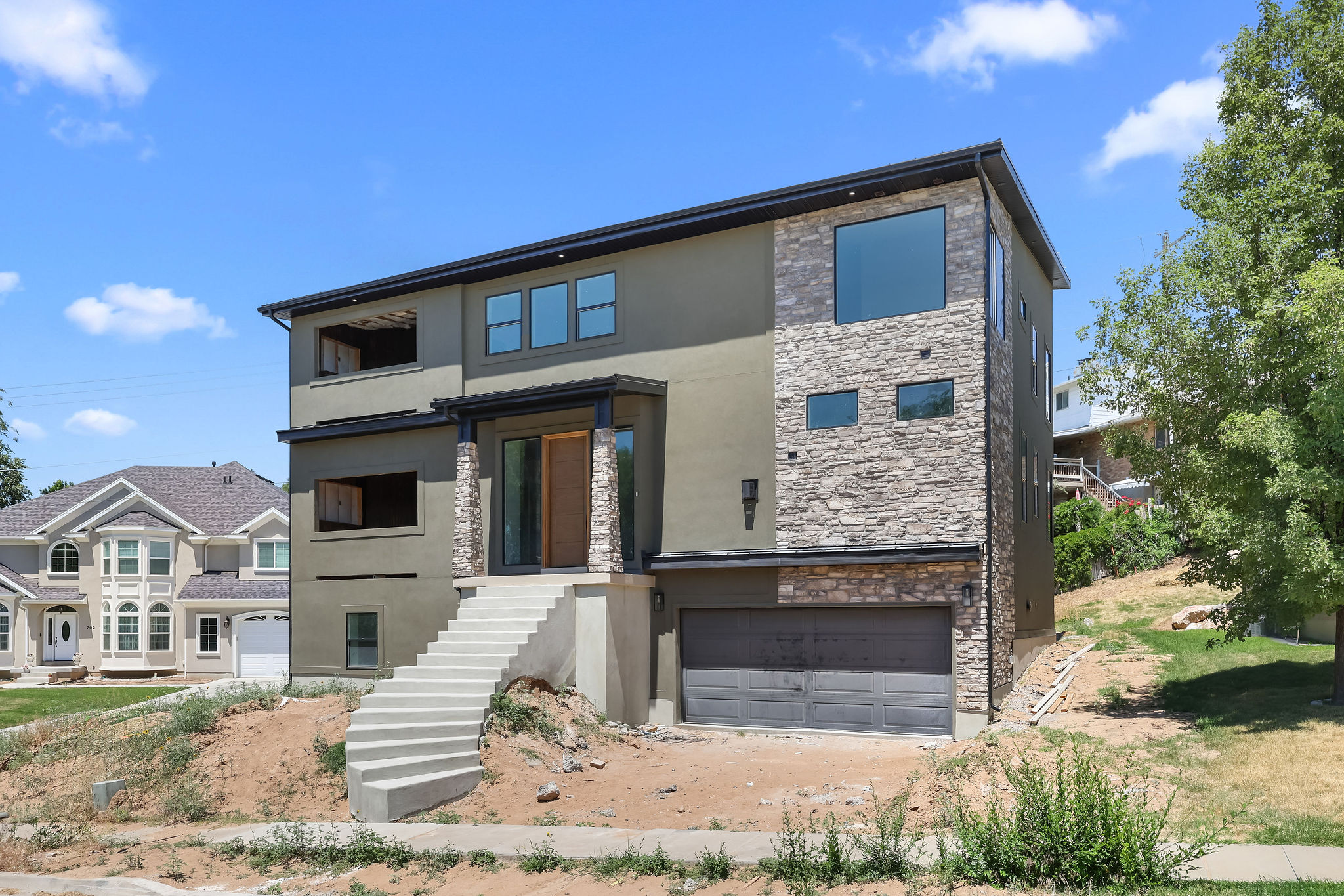 Contemporary multi-level residence featuring a stucco and stone veneer exterior