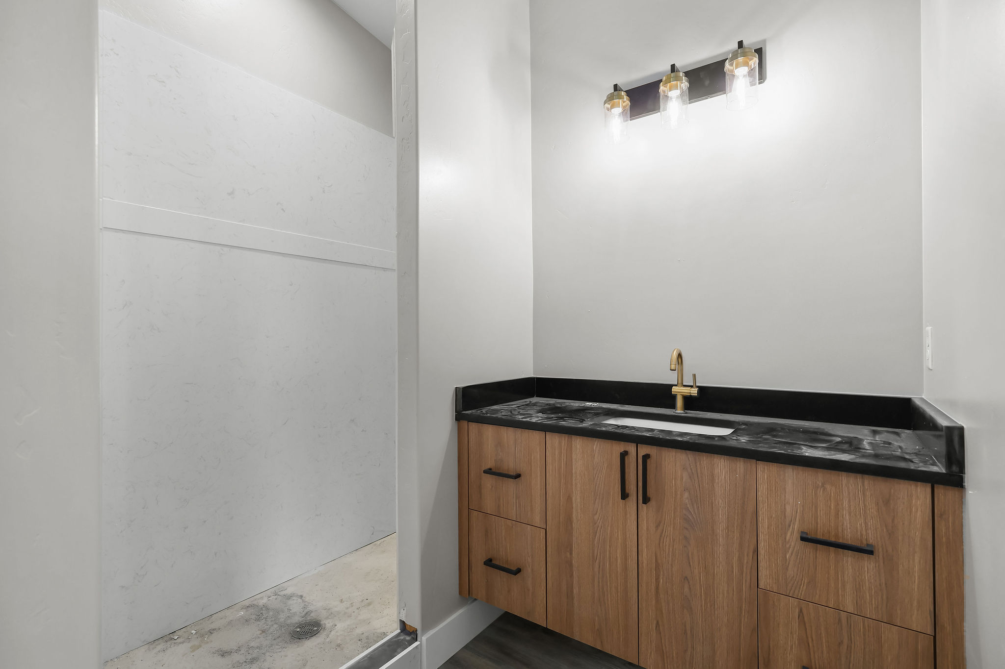 Floating wood-finish vanity with a dark countertop and integrated sink