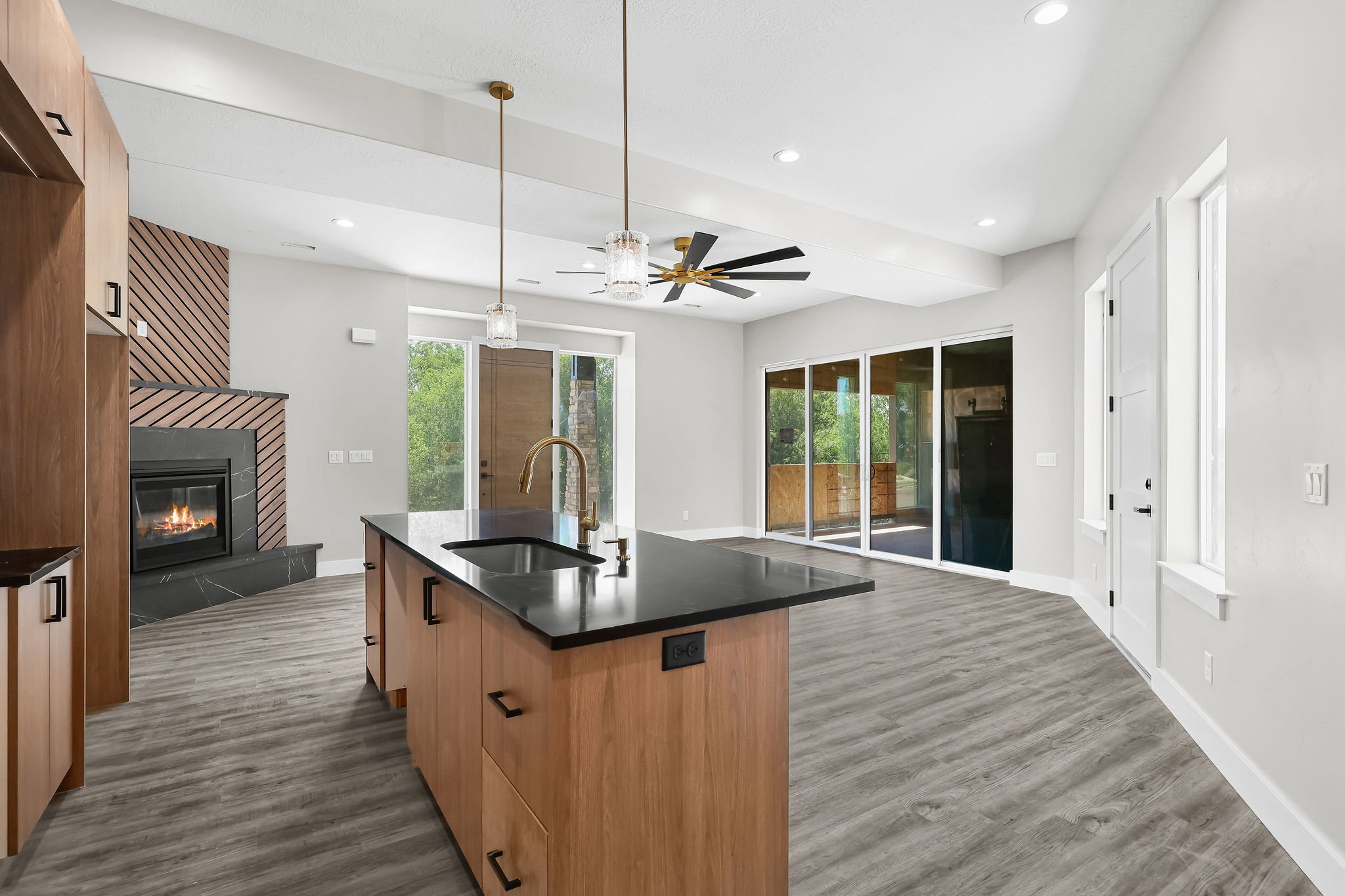 Open-concept living space with a central kitchen island featuring a black countertop and integrated sink