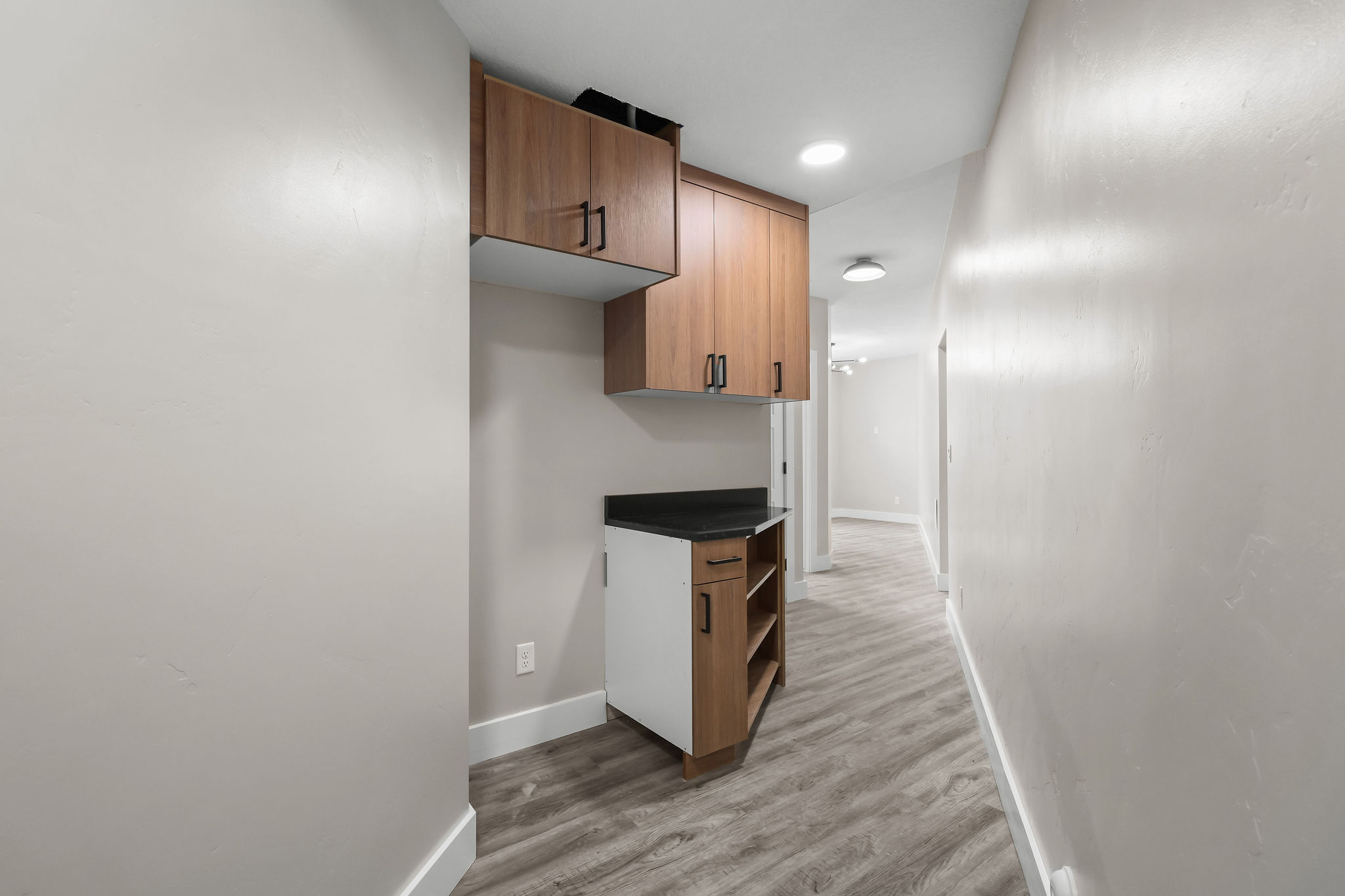Hallway featuring built-in cabinetry with wood-finish doors and matte black hardware
