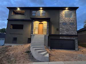 Contemporary exterior showcasing a stone facade accent, integrated garage, and concrete steps leading to the main entrance