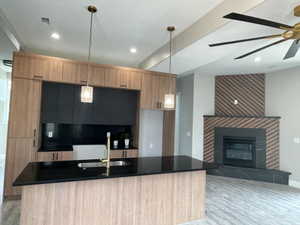 Open-concept living space featuring a modern kitchen island with black quartz countertop and undermount sink, complemented by gold-toned pendant lighting