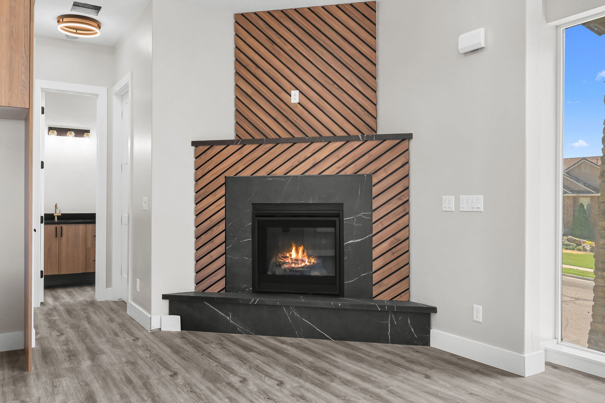 Contemporary fireplace featuring black-veined stone surround and hearth, accented by a diagonal wood-slat design