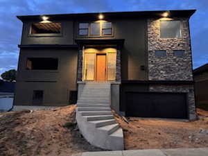 Contemporary facade featuring dark stucco and natural stone accents