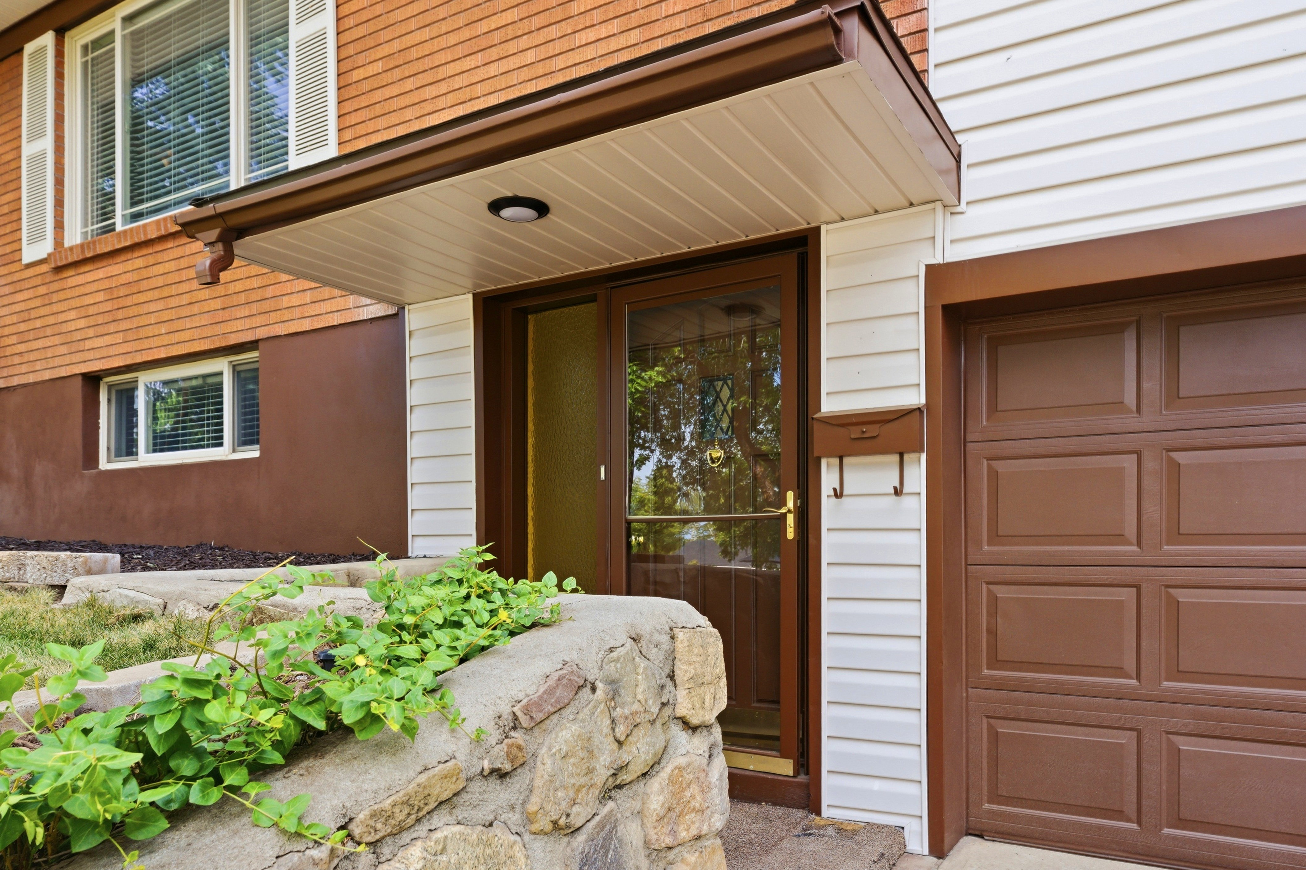 The property entrance features a covered porch, an attached garage with a brown panel door, and white siding