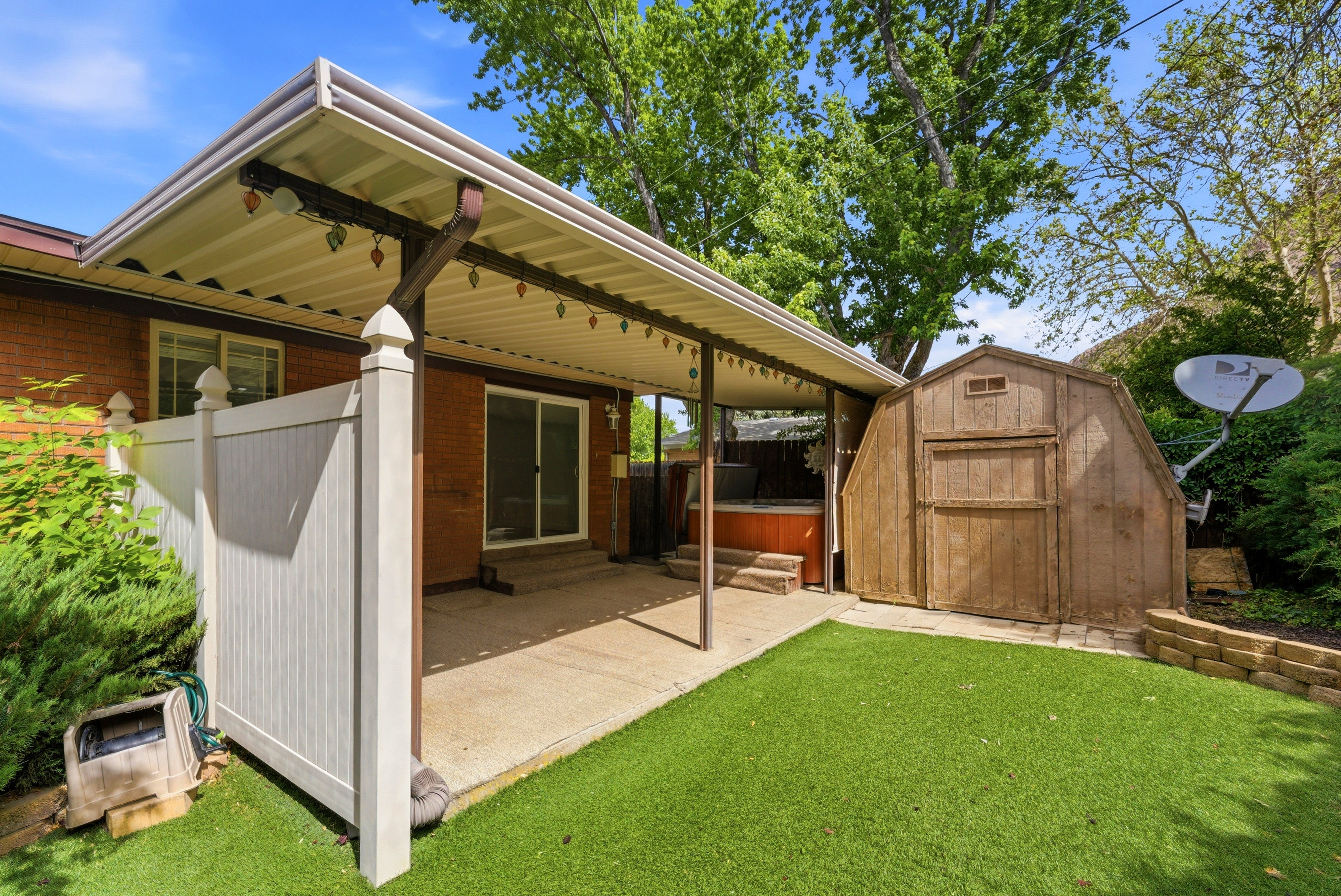 Fenced backyard featuring a covered patio, built-in hot tub, and a storage shed