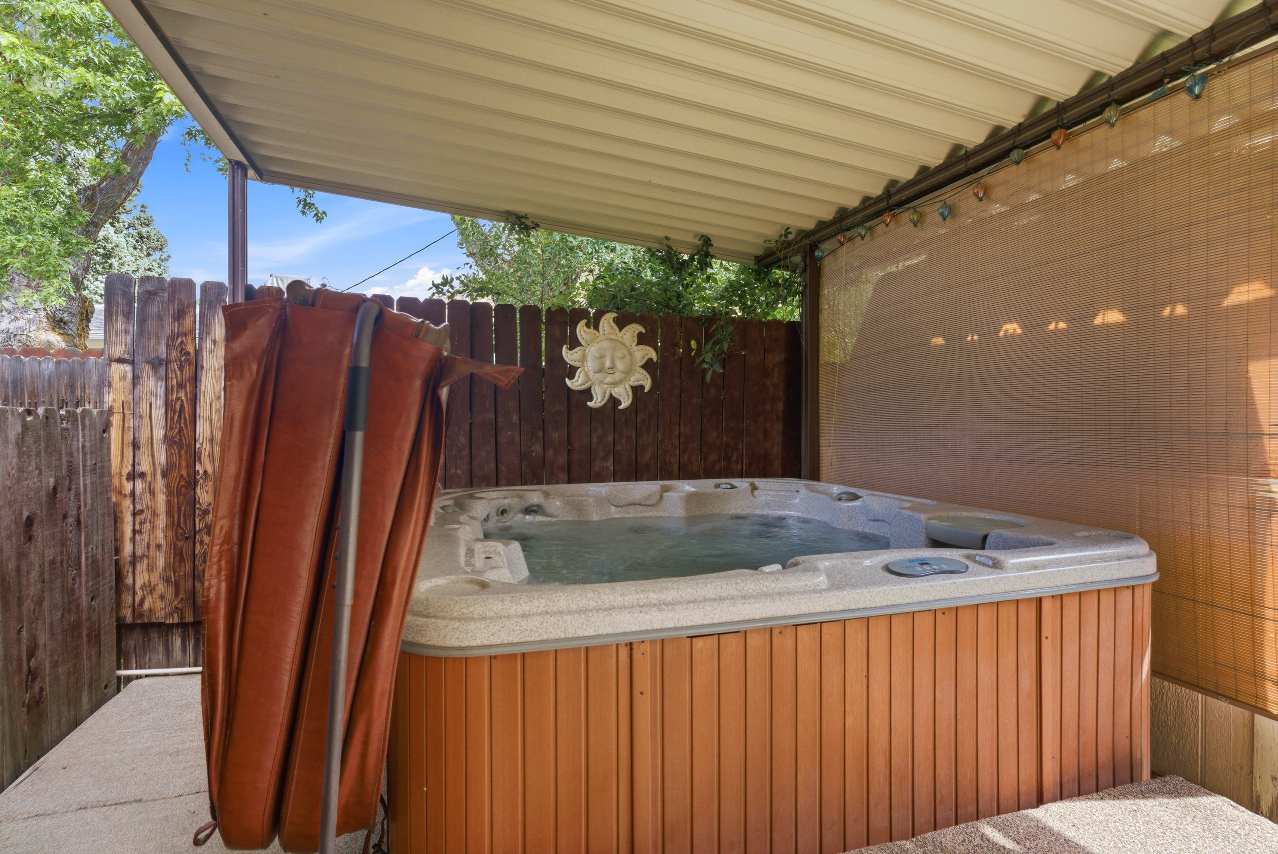 Outdoor hot tub featuring a light-colored shell and wood-look paneling, set on a concrete patio
