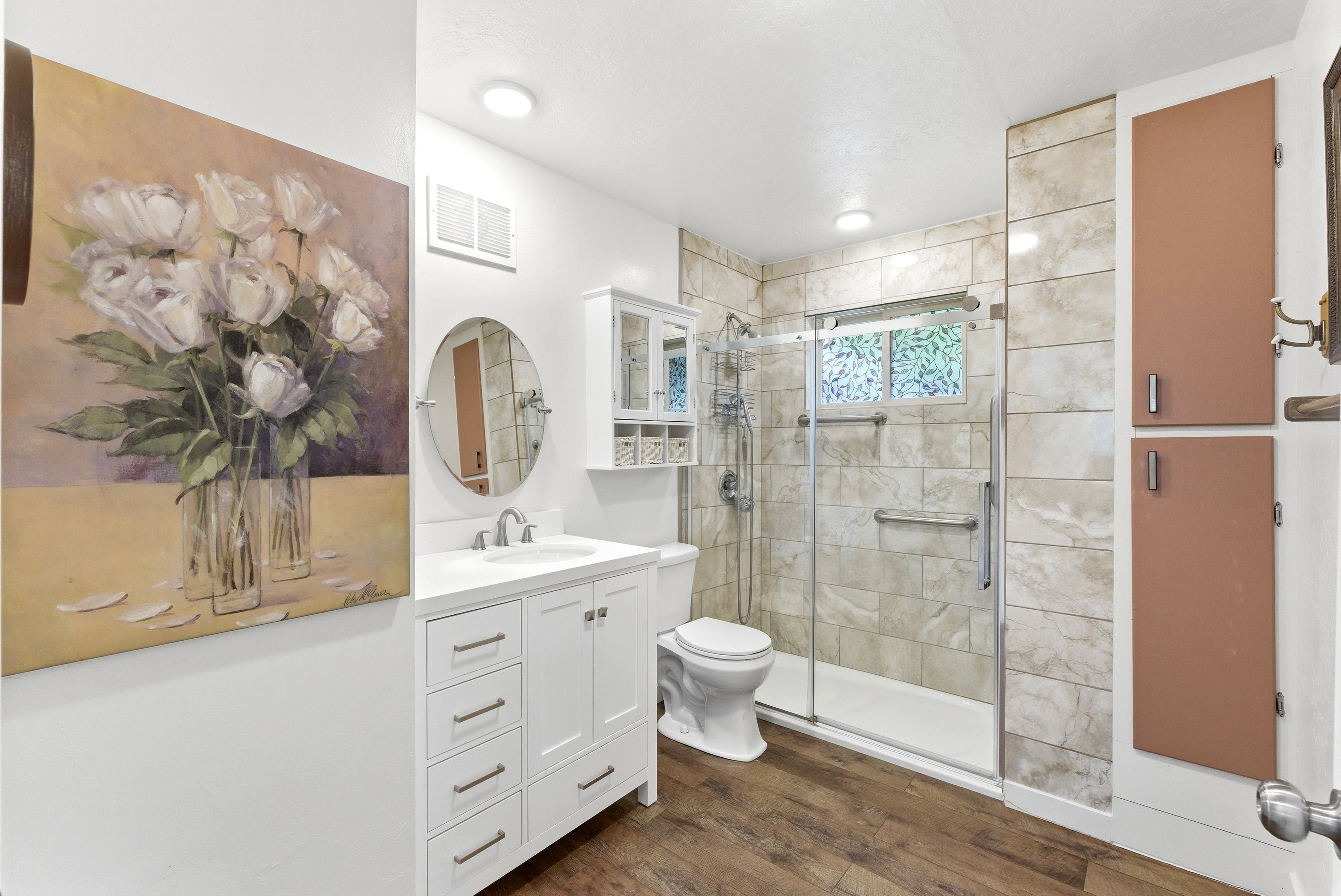 White vanity with ample drawer storage and a round mirror