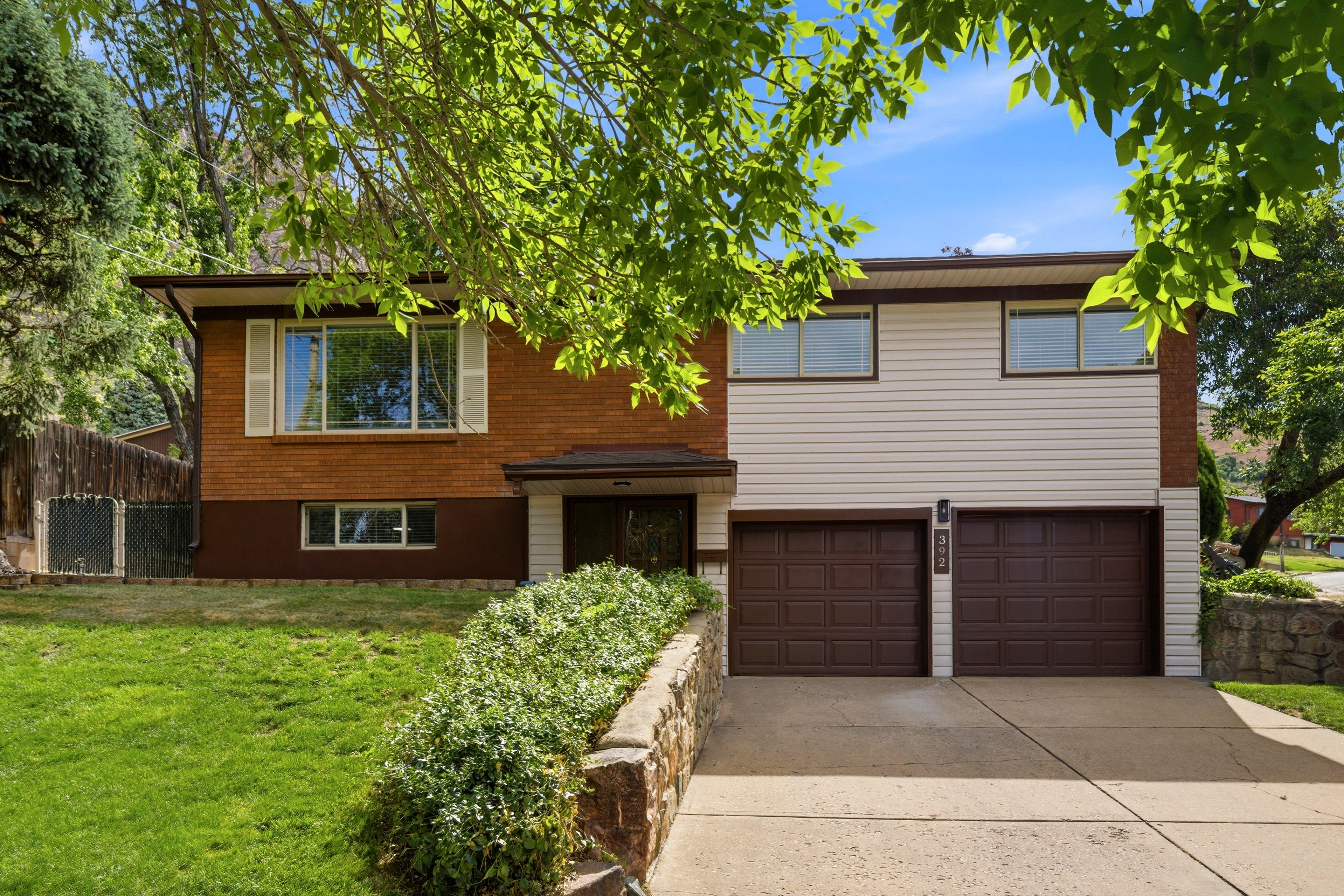 Split-level residence featuring a brick and siding exterior, an attached two-car garage, and a concrete driveway