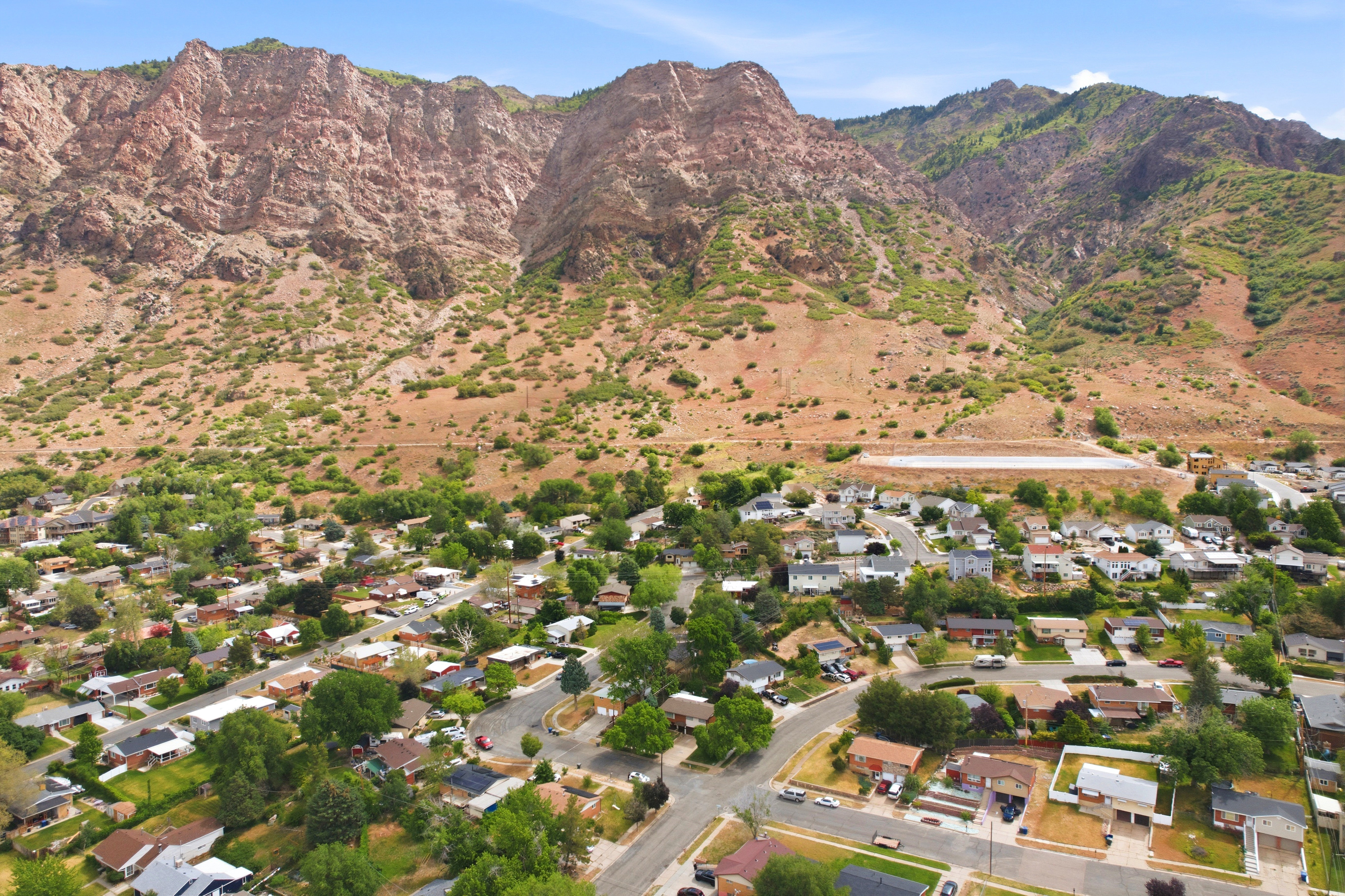 Residential neighborhood with mature trees, surrounded by rugged mountain terrain
