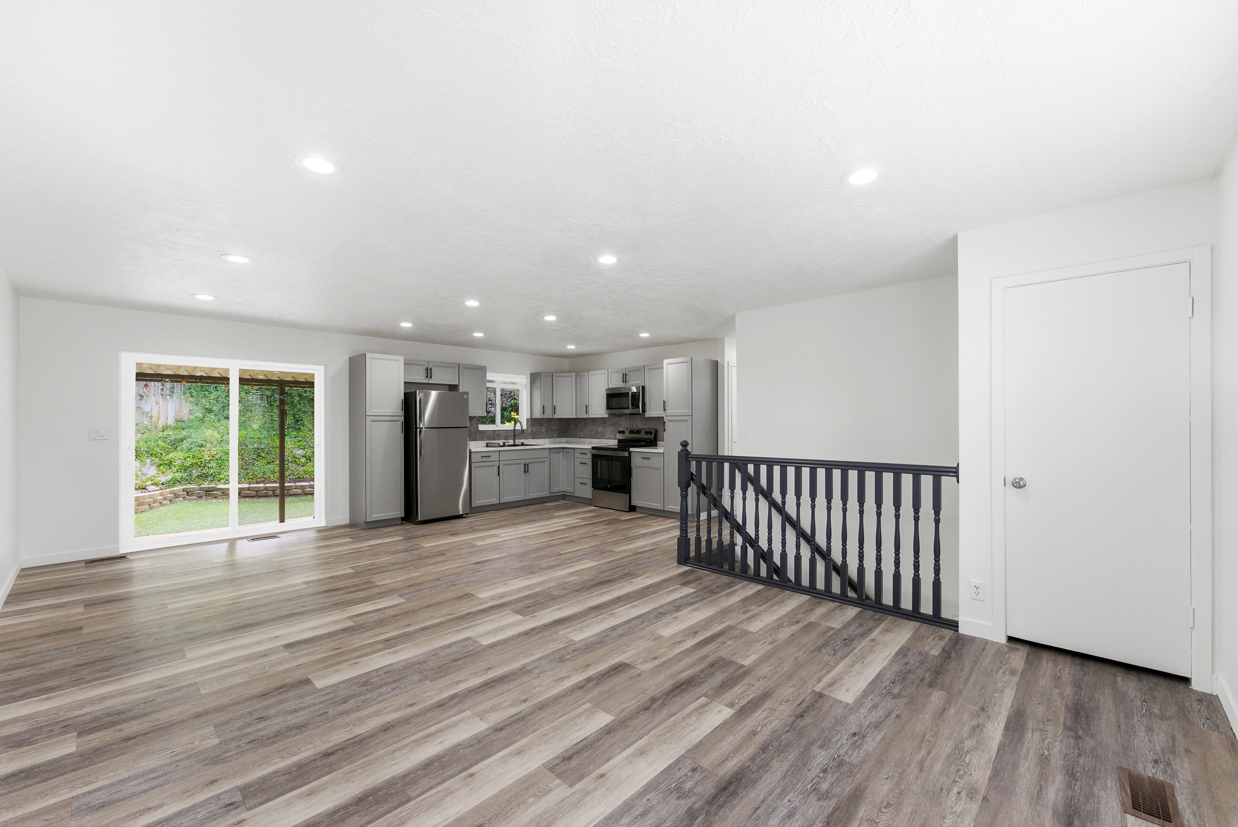 Open-concept living area featuring wood-finish flooring, recessed lighting, and a sliding glass door to the backyard