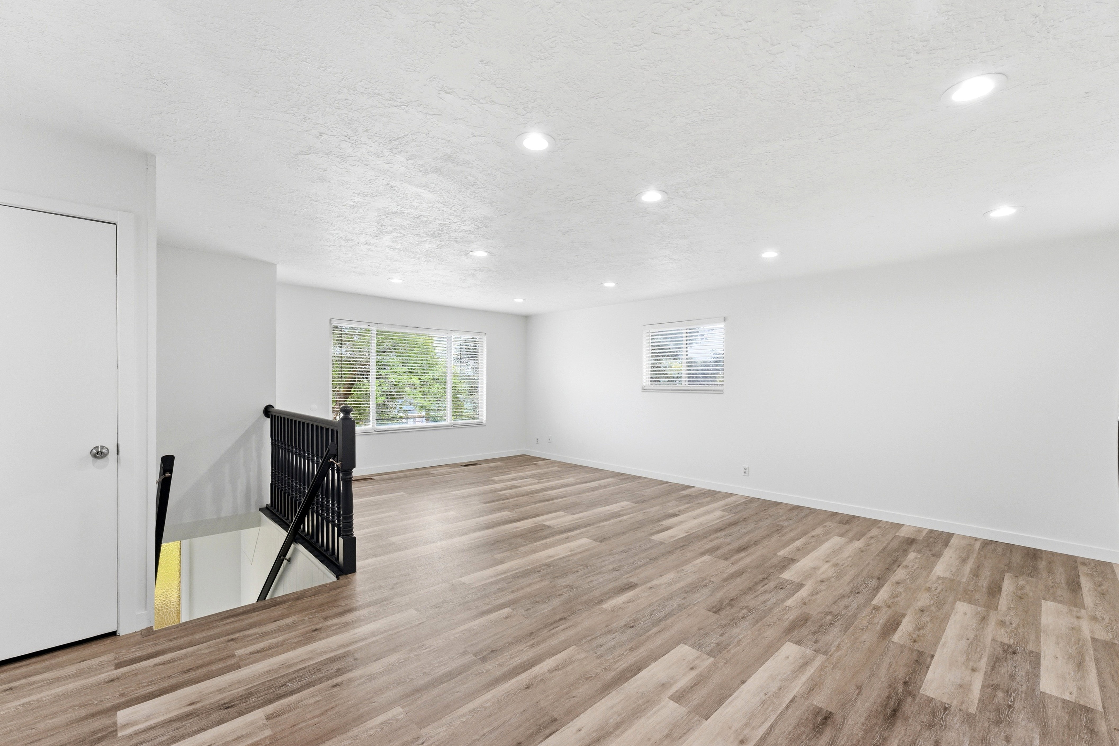 Spacious room with wood-finish flooring, recessed lighting, and white walls