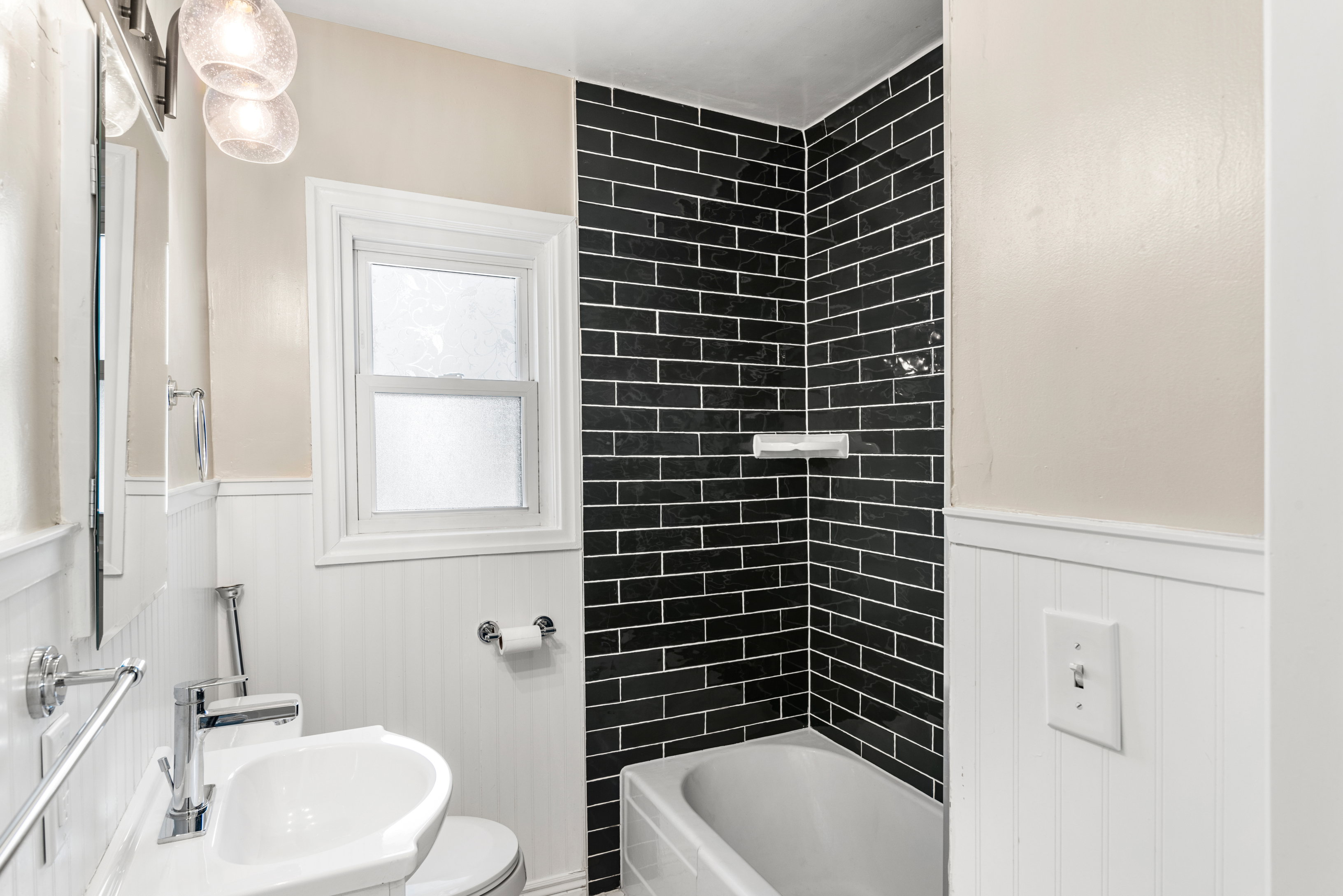 Main floor bathroom featuring custom colored subway tile, two-tone wainscot walls, and tile floor