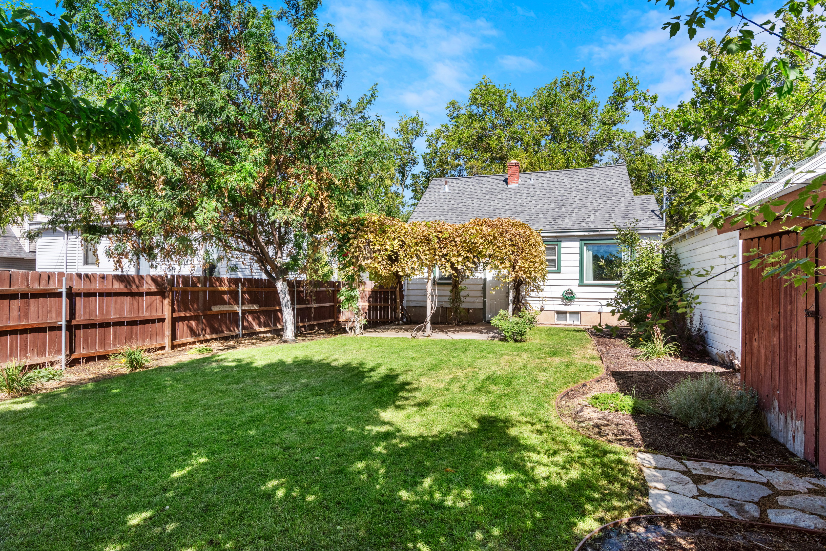 Secluded and fully fenced backyard with cottage style grape arbor patio cover