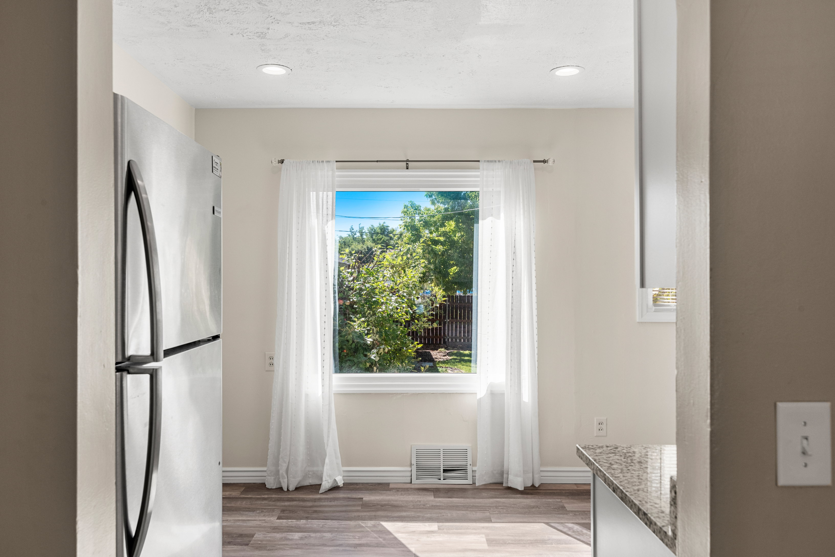Remodeled kitchen featuring white cabinetry, granite countertops, subway tile backsplash, stainless steel appliances, and recessed lighting