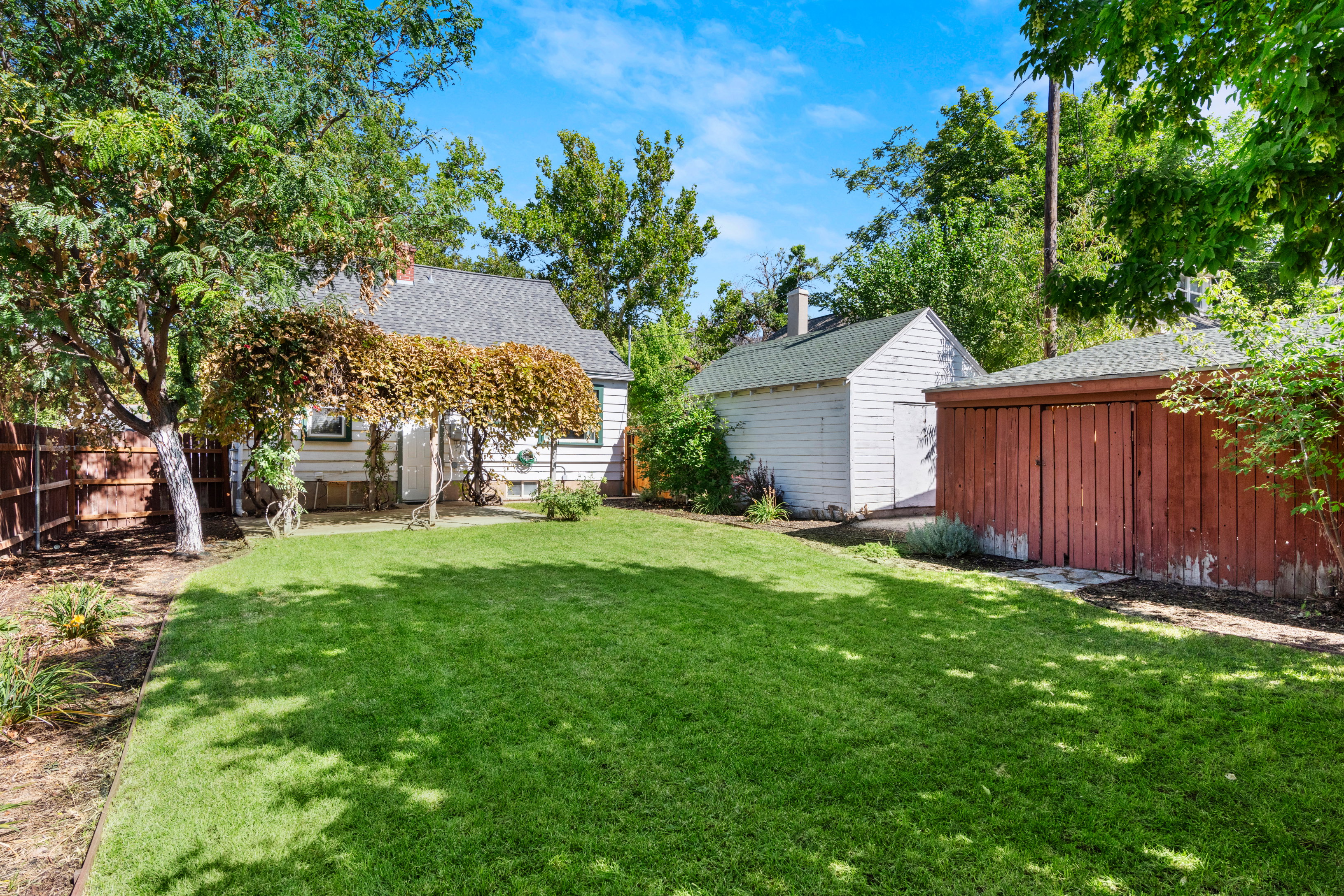 Secluded and fully fenced backyard with cottage style grape arbor patio cover