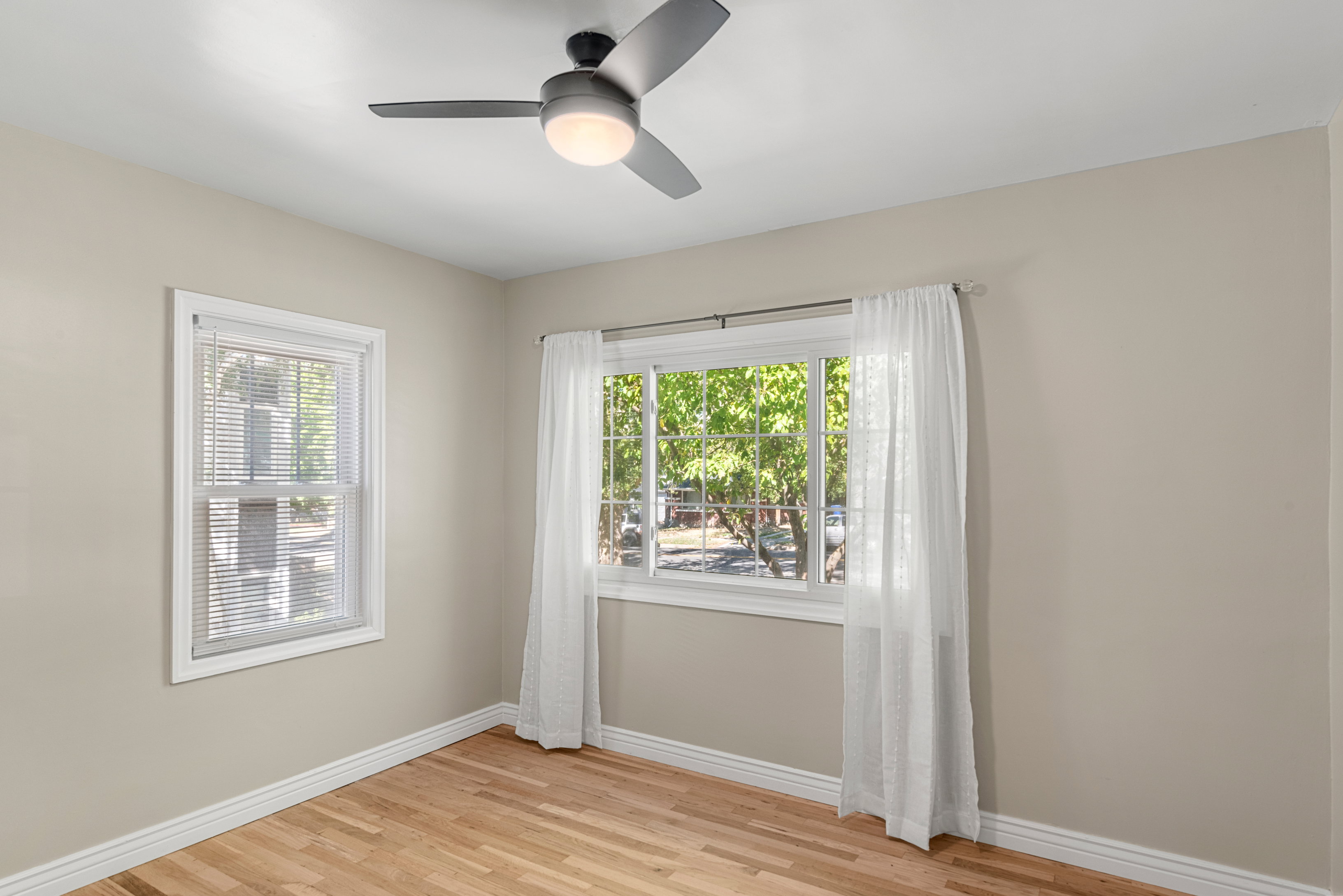 Light-filled main floor bedroom featuring original hardwood floors, two-tone paint, and LED lighting