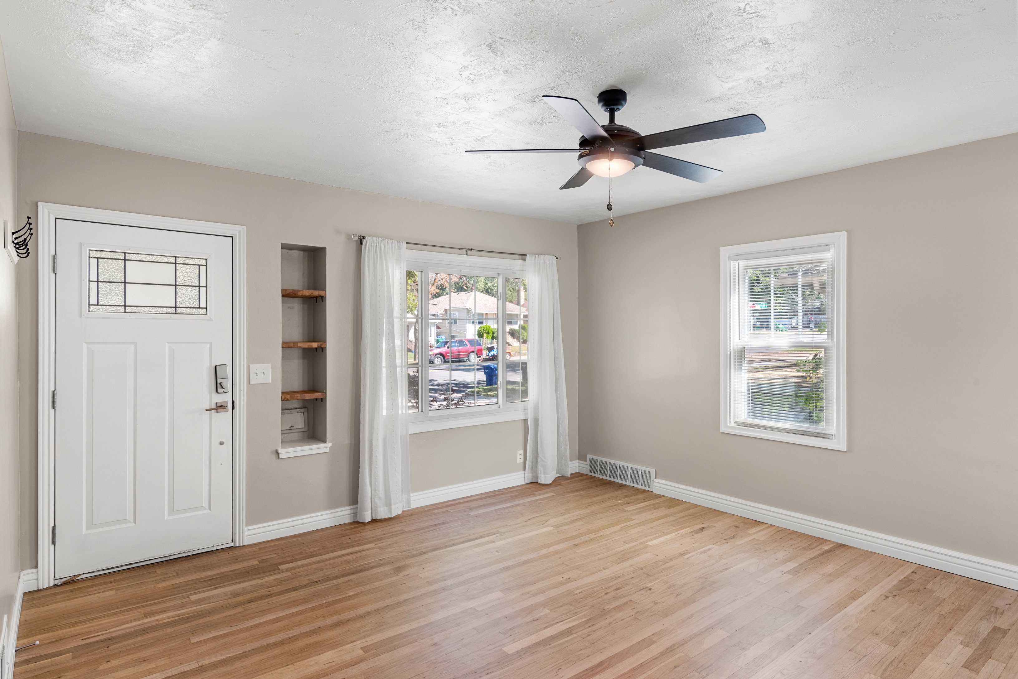 Main floor living room featuring ample natural light, ceiling fan, custom shelving, two-tone paint, and original hardwood floors