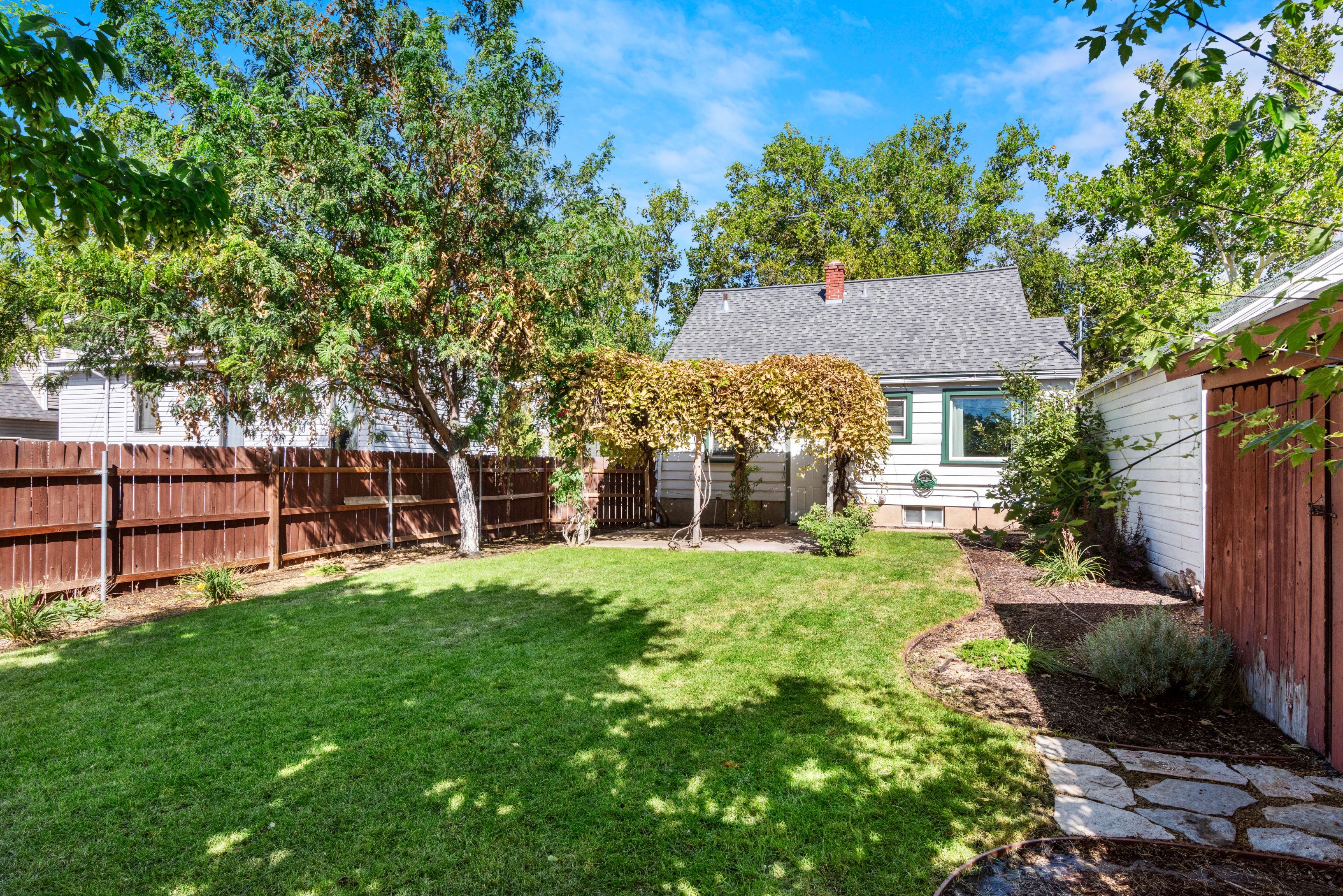 Secluded and fully fenced backyard with cottage style grape arbor patio cover