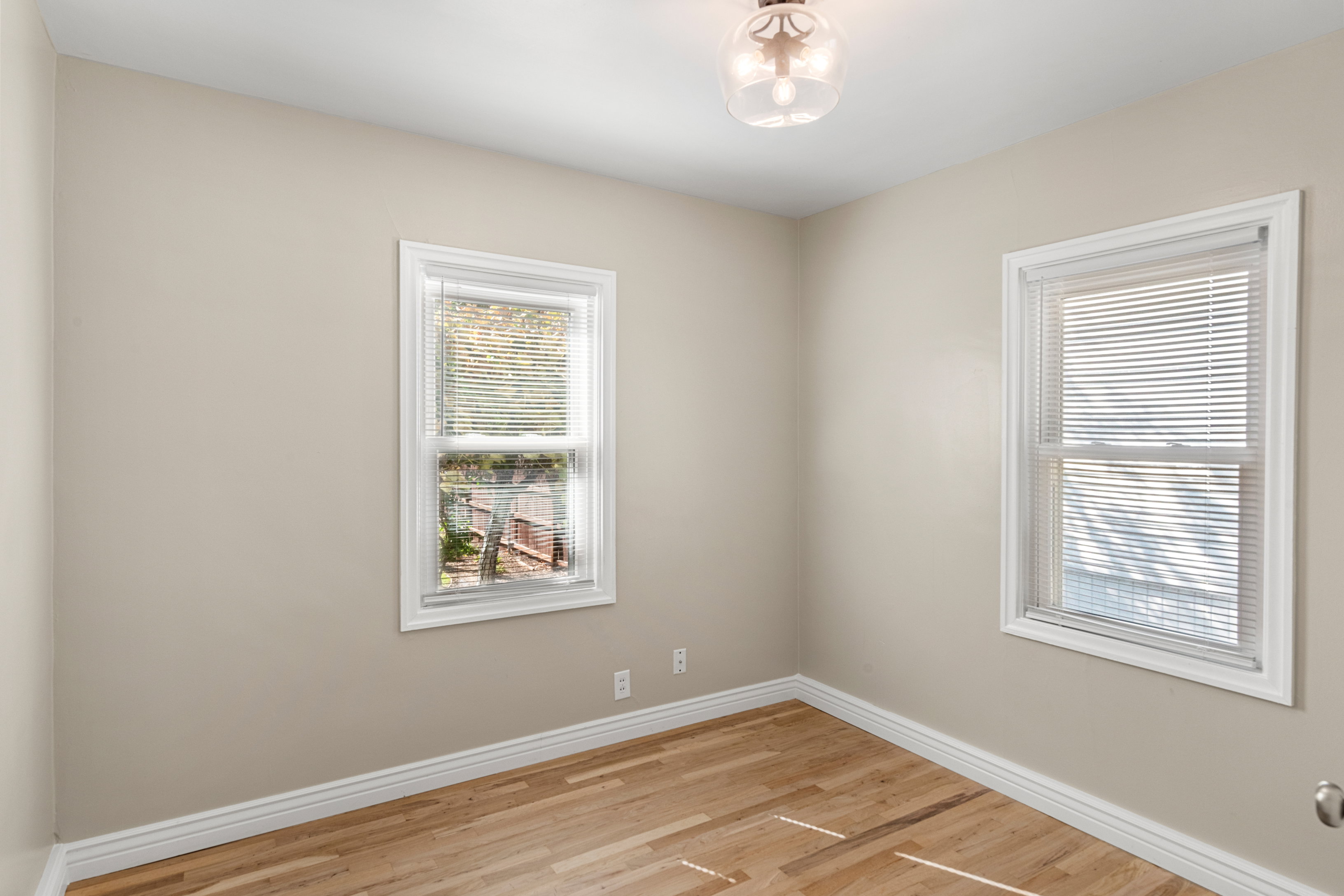 Main floor bedroom featuring original hardwood floors, ample natural light, and a view of the backyard