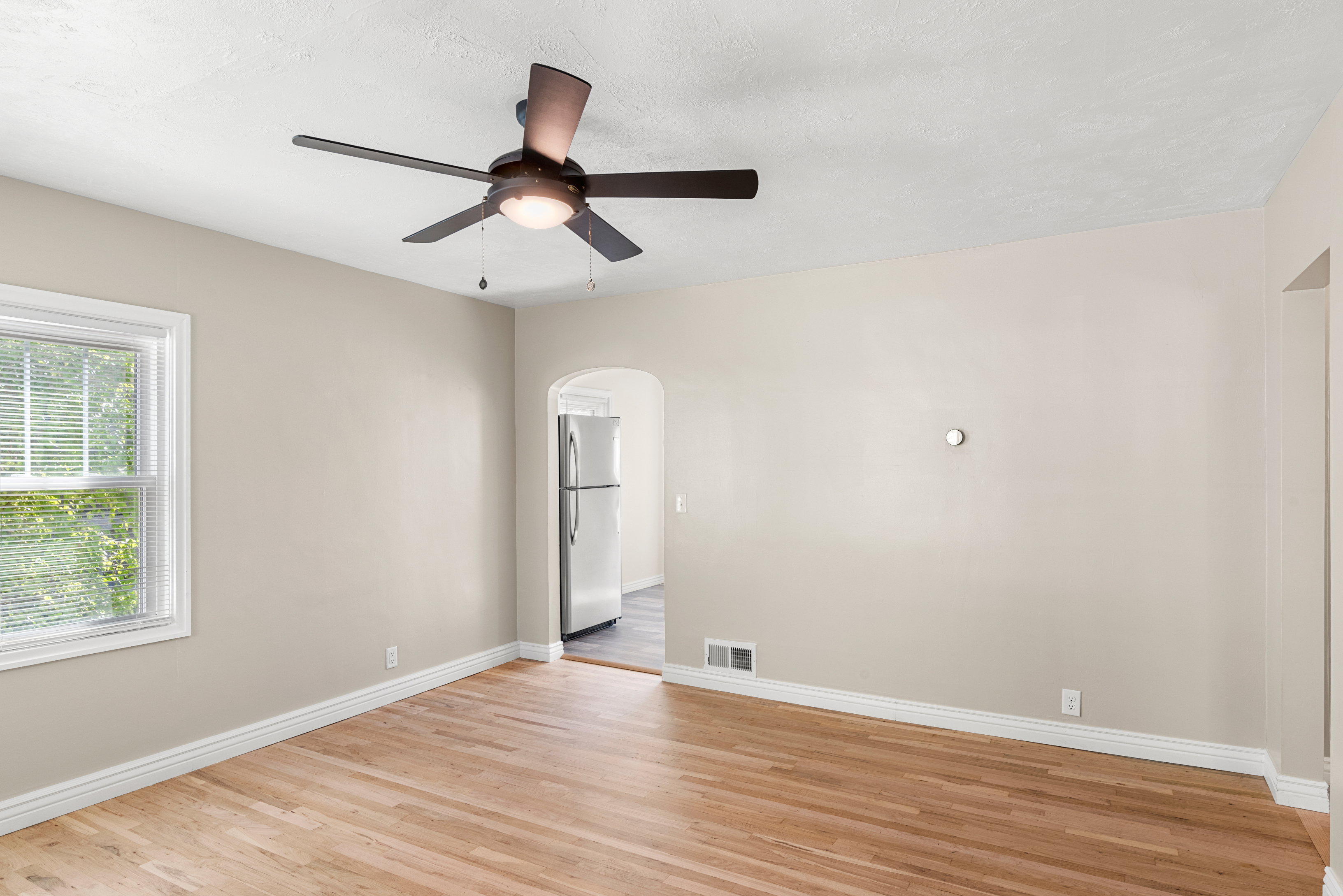 Main floor living room featuring ample natural light, ceiling fan, custom shelving, two-tone paint, and original hardwood floors