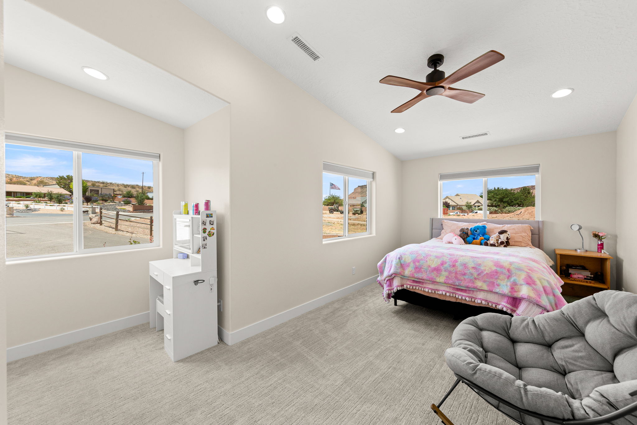 Spacious room featuring multiple windows, recessed lighting, vaulted ceilings, and a ceiling fan