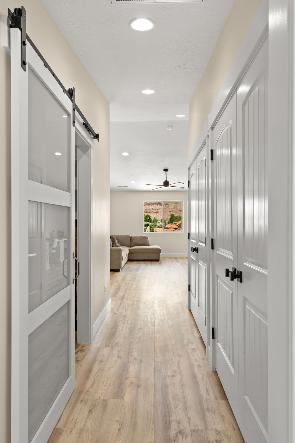 Hallway featuring wood-finish flooring, white paneled doors, and recessed lighting