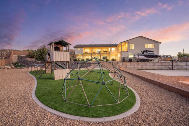 Expansive backyard featuring a manicured lawn area, gravel pathways, and a multi-level playset