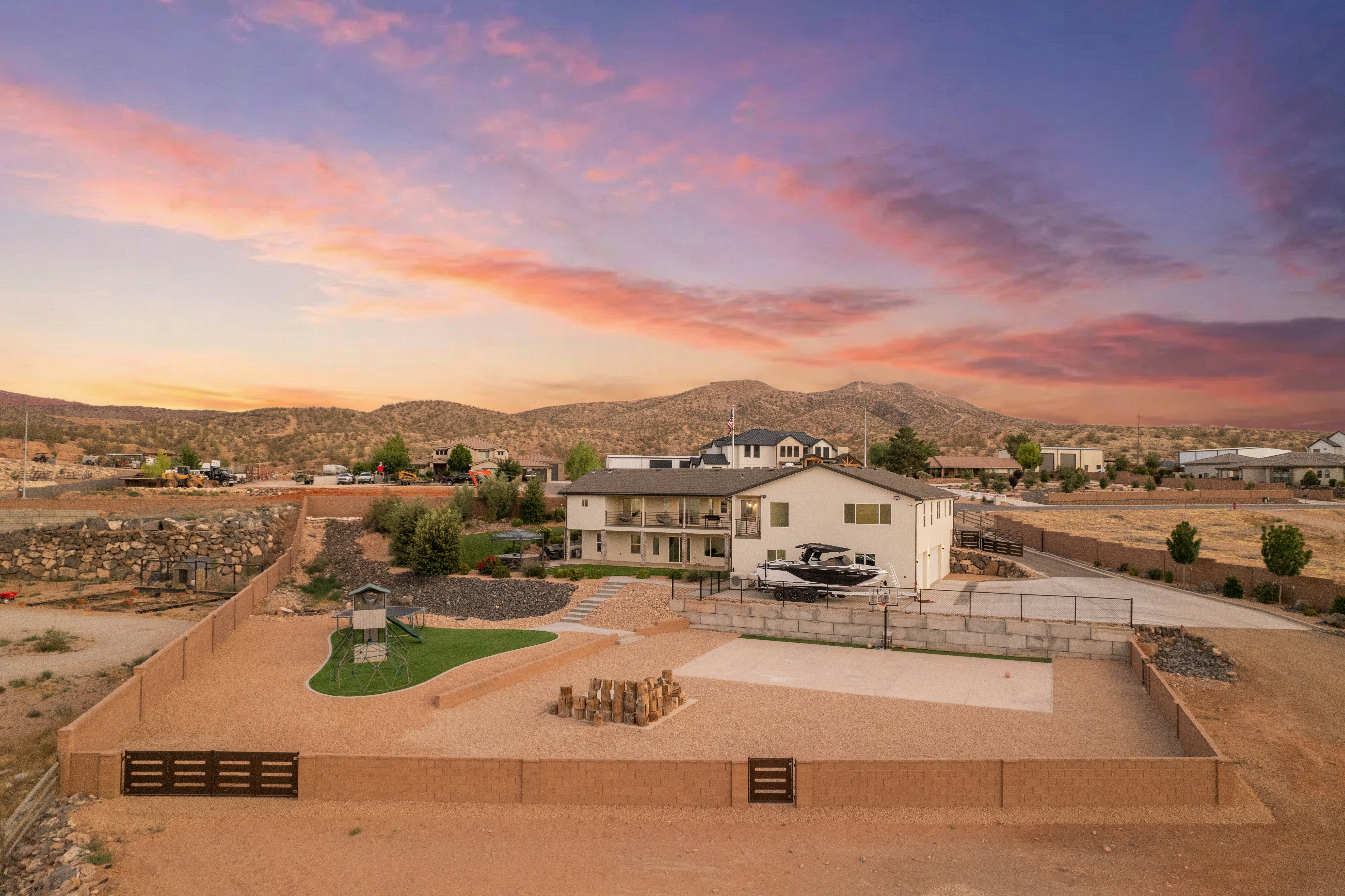 Spacious property featuring a multi-level home with balconies, extensive hardscaping, a large fenced yard, and a concrete patio