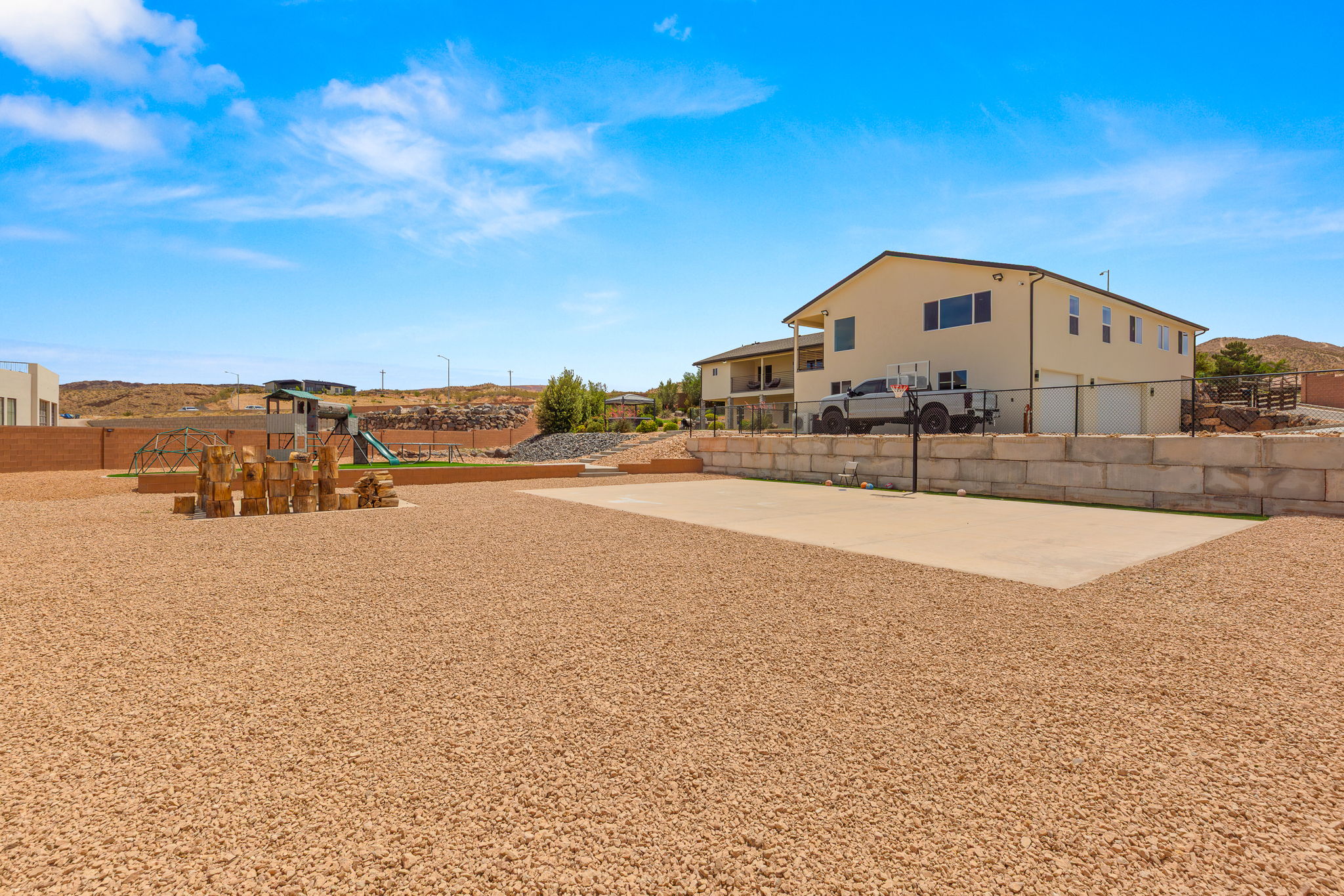 Expansive gravel yard featuring a concrete sports court and a dedicated play area with artificial turf
