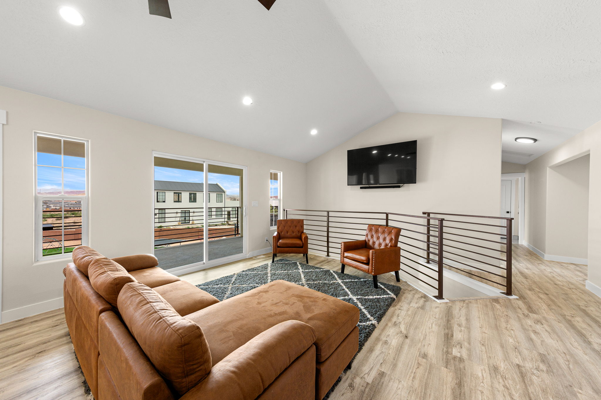 Spacious open-concept room featuring vaulted ceilings, recessed lighting, and wood-finish flooring