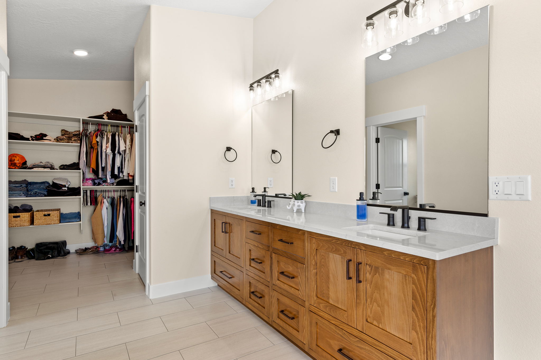 Dual vanity featuring wood cabinetry, white stone countertops, and matte black fixtures