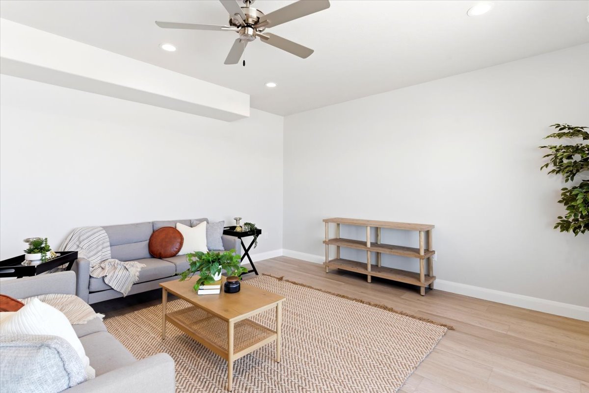 Open-concept living space featuring light wood-finish flooring, recessed lighting, a ceiling fan, and white baseboards