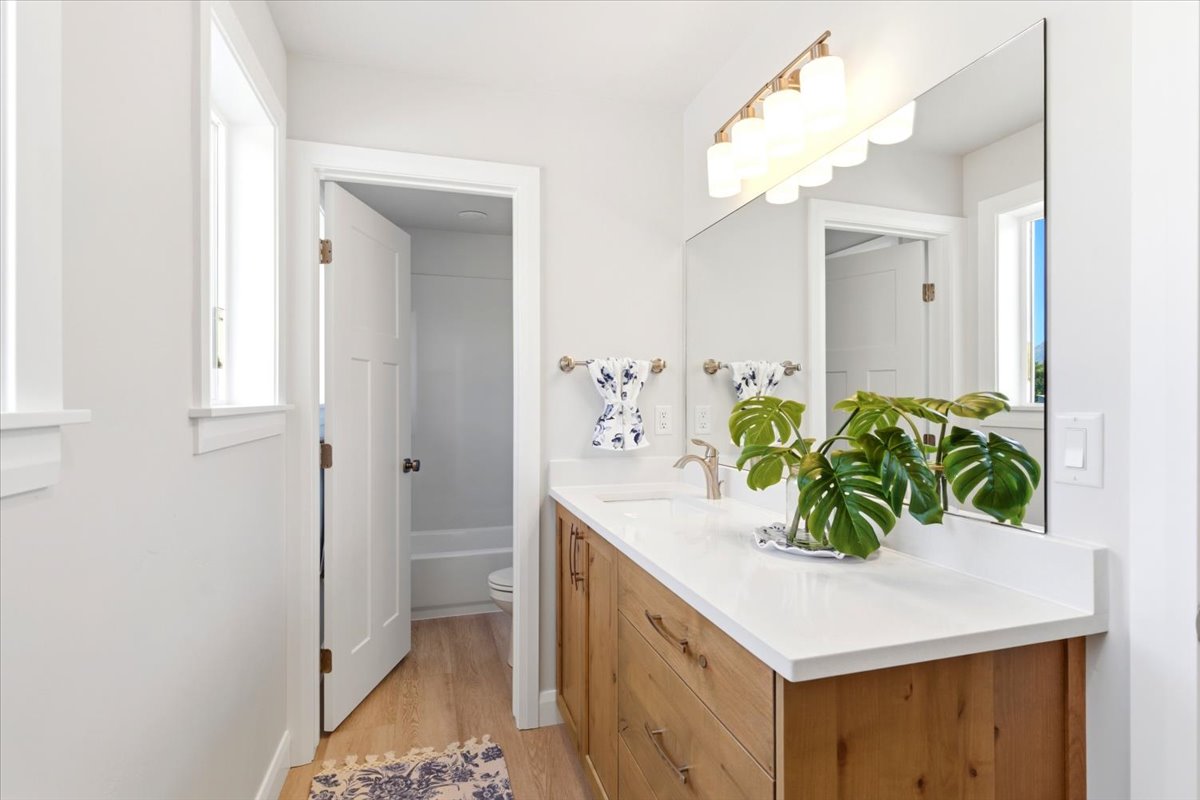 Bathroom featuring a wood-finish vanity with drawer storage, a white countertop, and an undermount sink with a single-handle faucet