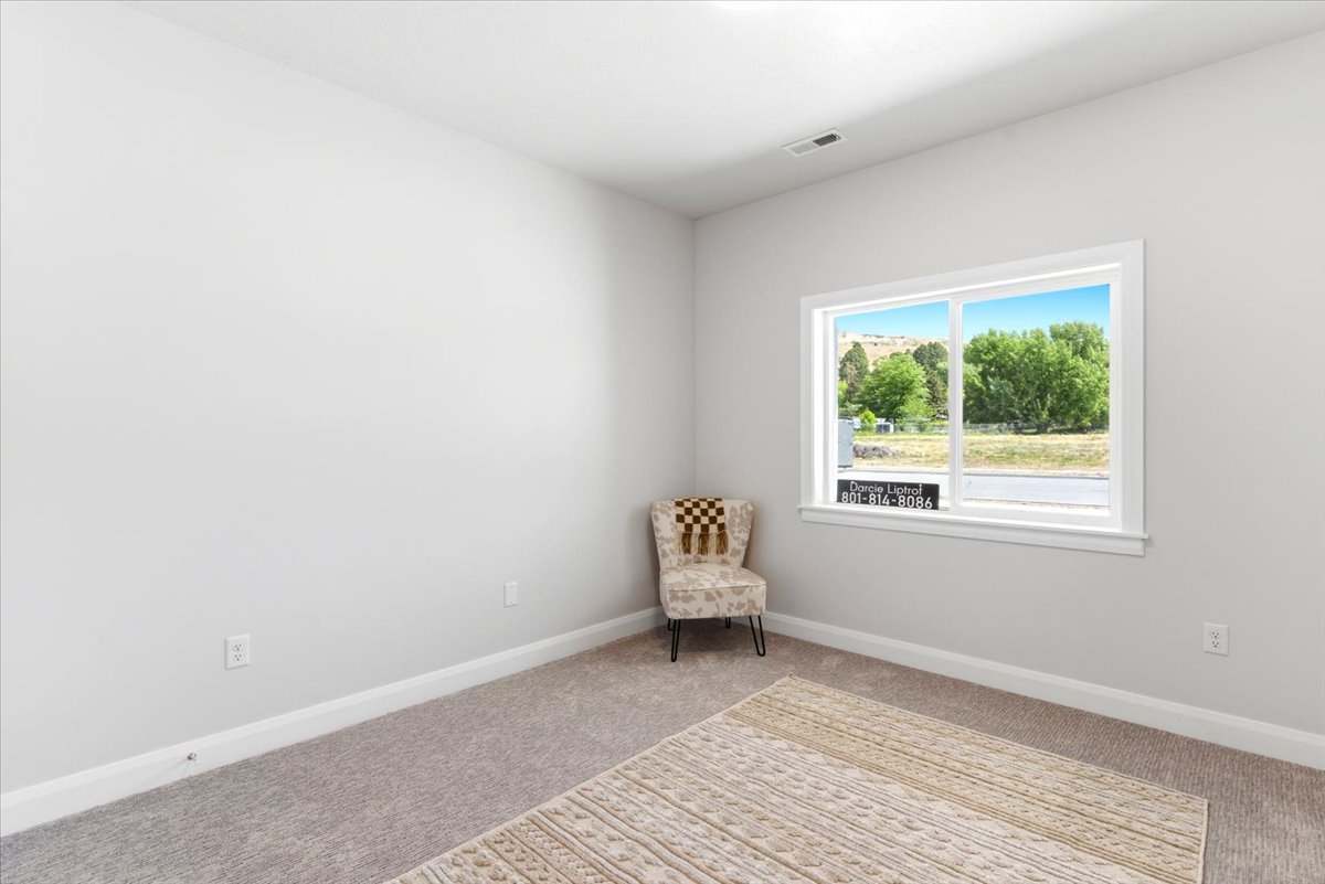 Room featuring light gray wall paint, white trim, gray carpet flooring, and a large window with a natural landscape