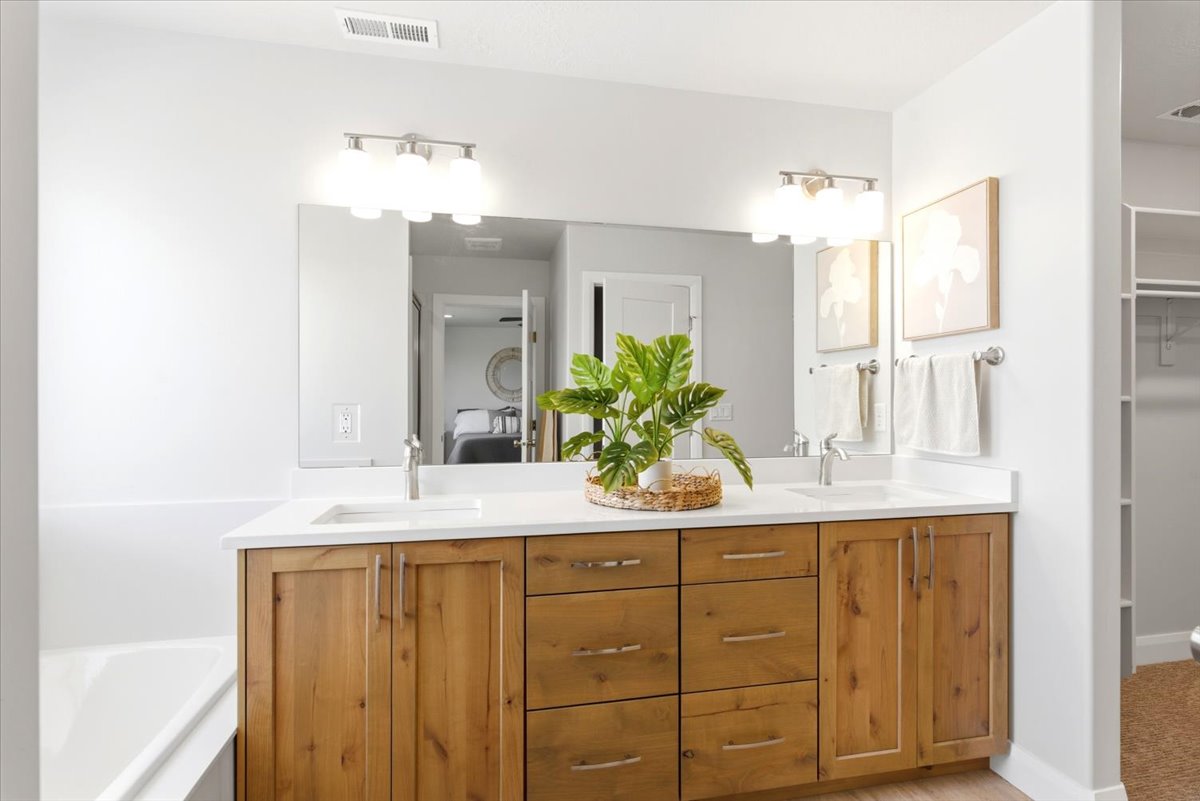 Dual vanity with wood-finish cabinetry, white countertops, and undermount sinks