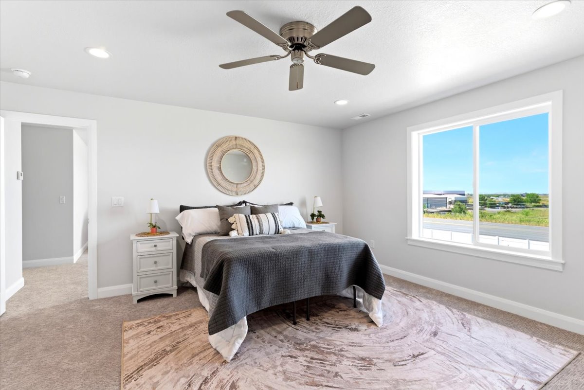 Spacious room featuring neutral carpeting, a large window, recessed lighting, and a ceiling fan
