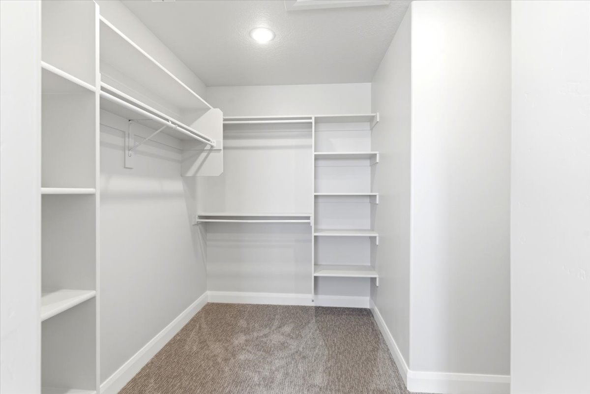 Walk-in closet featuring built-in shelving, white hanging rods, and recessed lighting