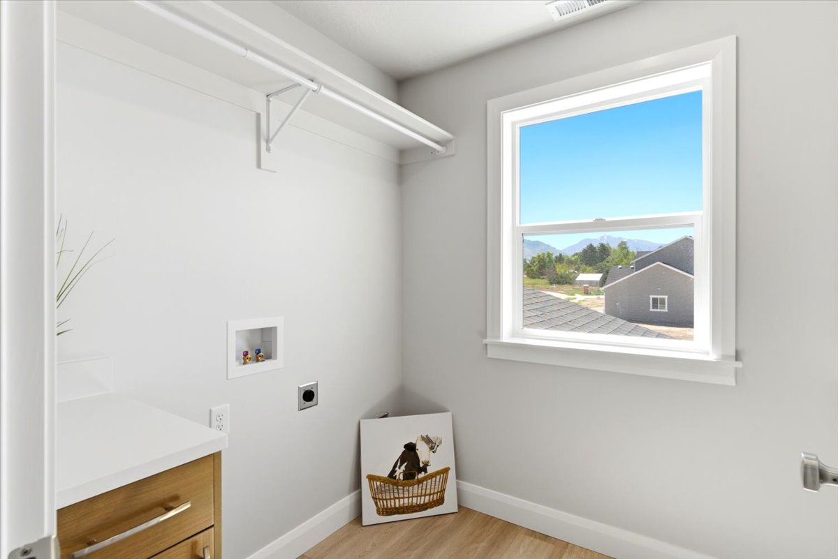 Laundry area featuring a window, built-in shelving, white countertop, and wood-finish cabinetry