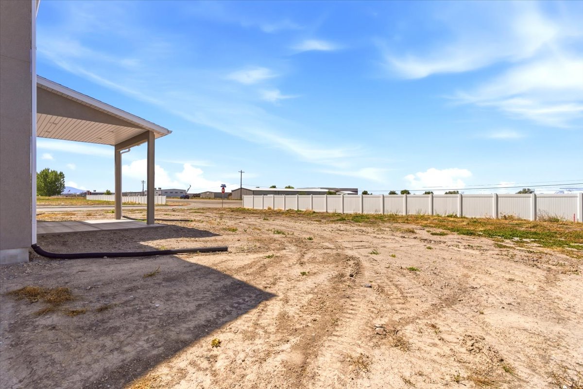 Rear patio area with a concrete slab, supporting columns, and a covered ceiling