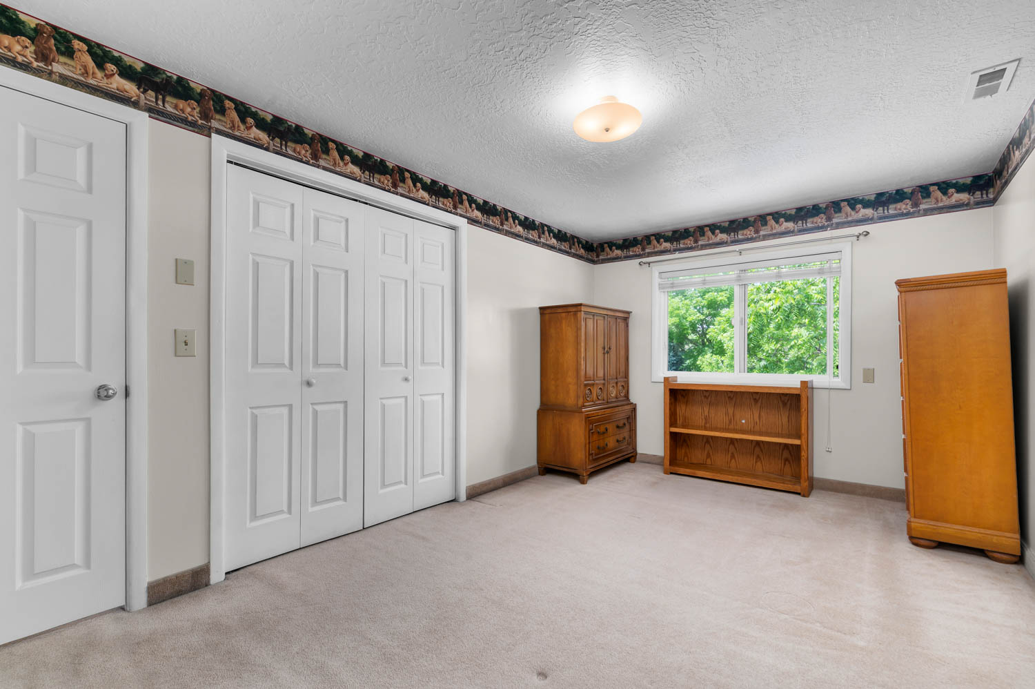 Neutral-toned carpeting spans the room, complemented by white walls and a patterned border