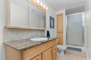 Bathroom featuring a light wood vanity with a stone countertop, an integrated sink, a chrome faucet, and a large mirrored medicine cabinet with overhead lighting