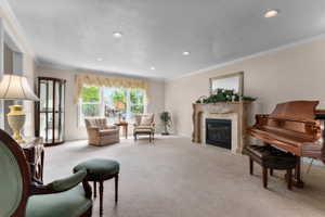 Spacious carpeted room featuring a decorative fireplace with an ornate mantel, large window with valance, recessed lighting, and crown molding